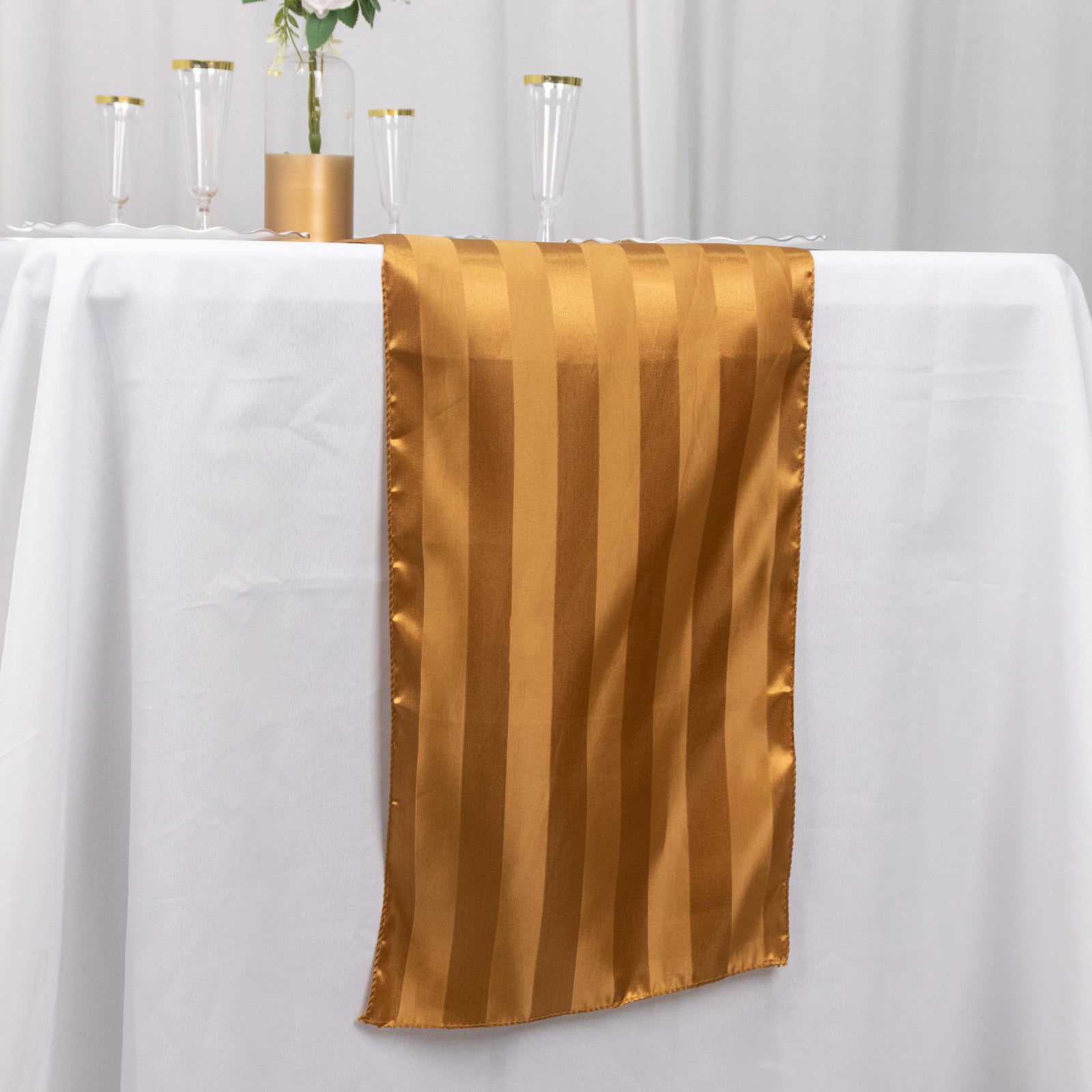 Gold satin stripe table runner on a white tablecloth.