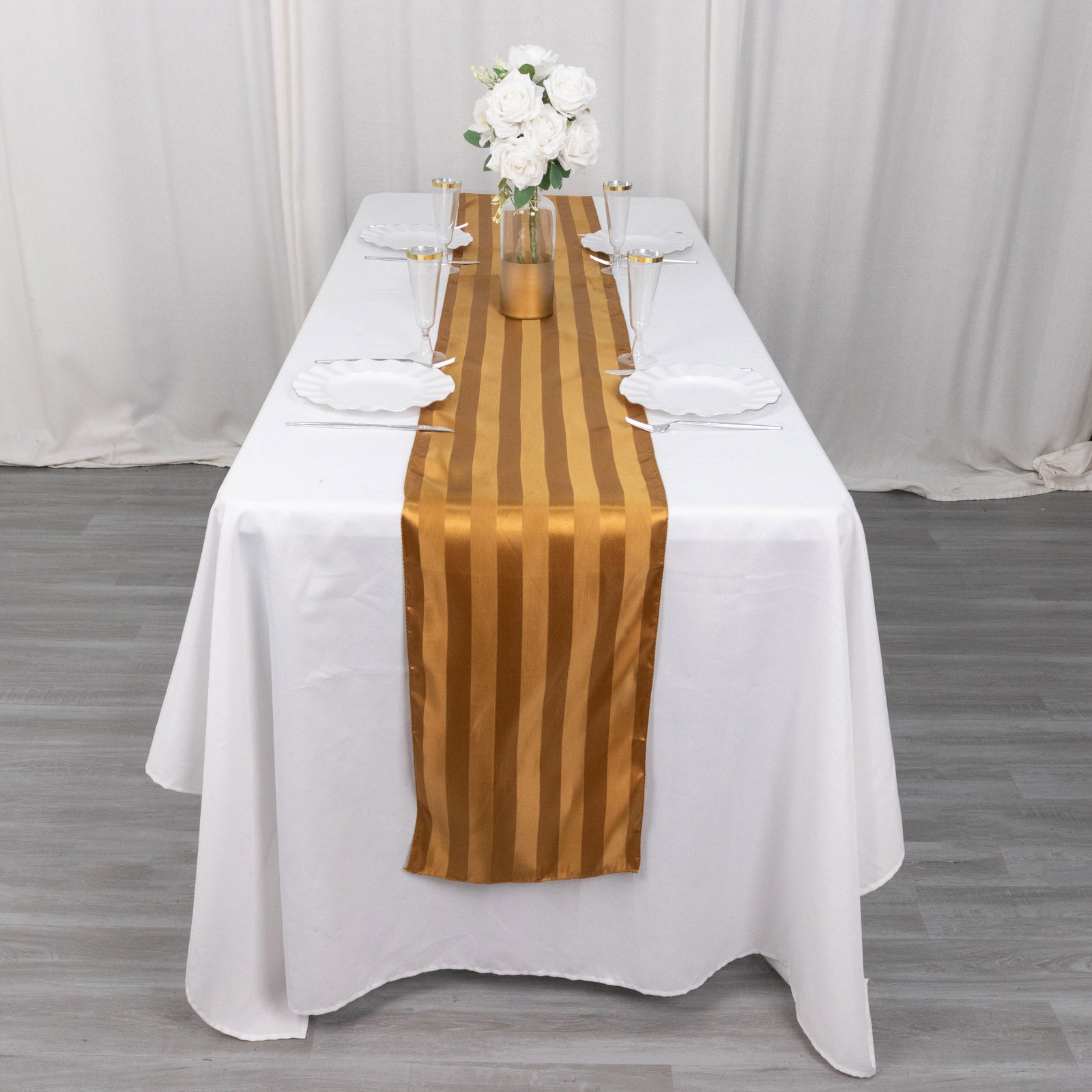 Gold satin stripe table runner on a white table, elegantly styled for events.