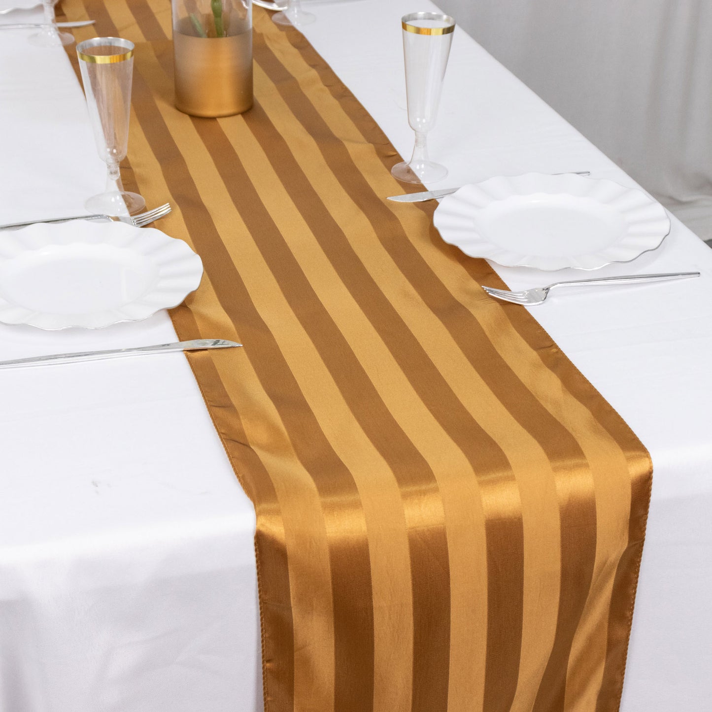 Gold satin stripe table runner on a dining table setting.