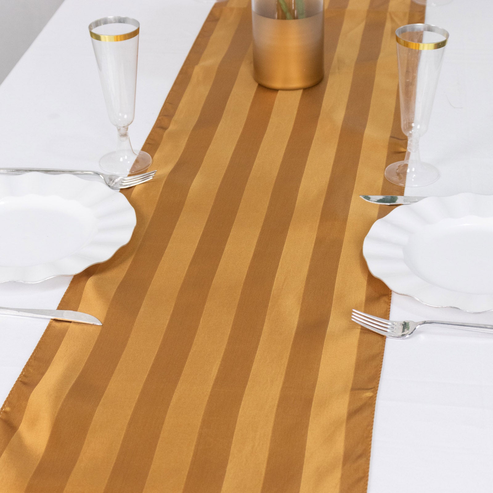 Gold satin stripe table runner on a white table setting.