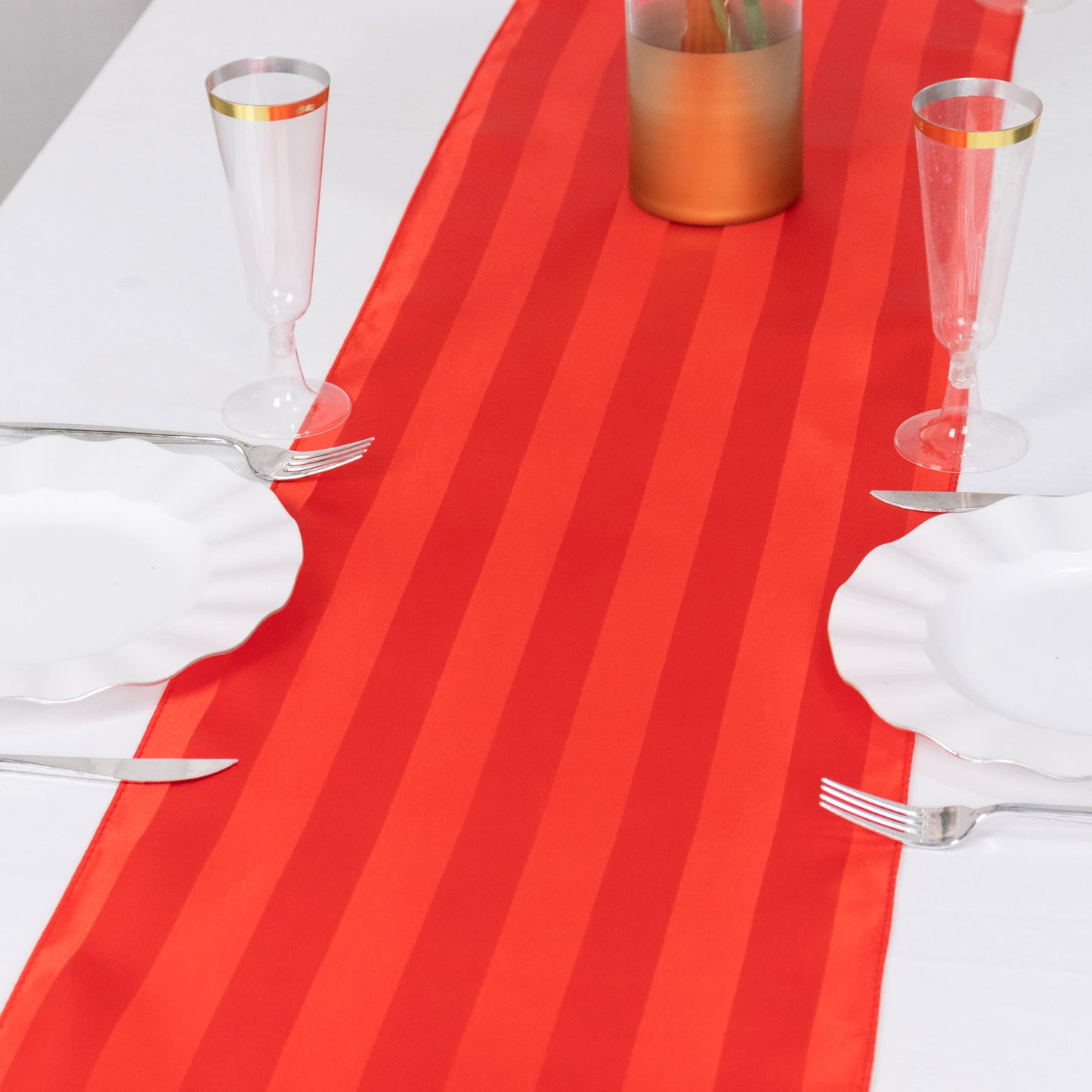 Red satin stripe table runner on a dining table setting.