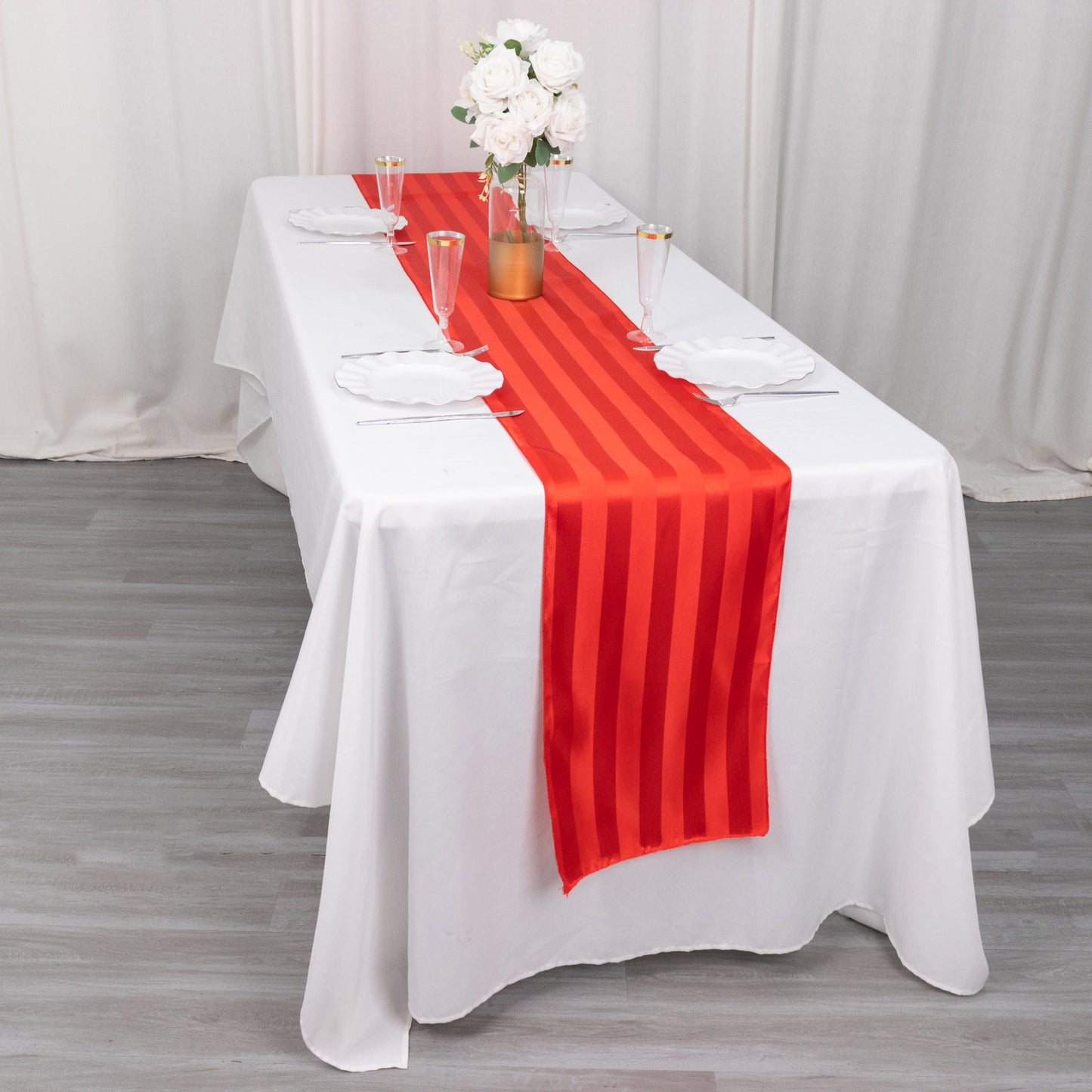 Red satin stripe table runner on a white tablecloth.