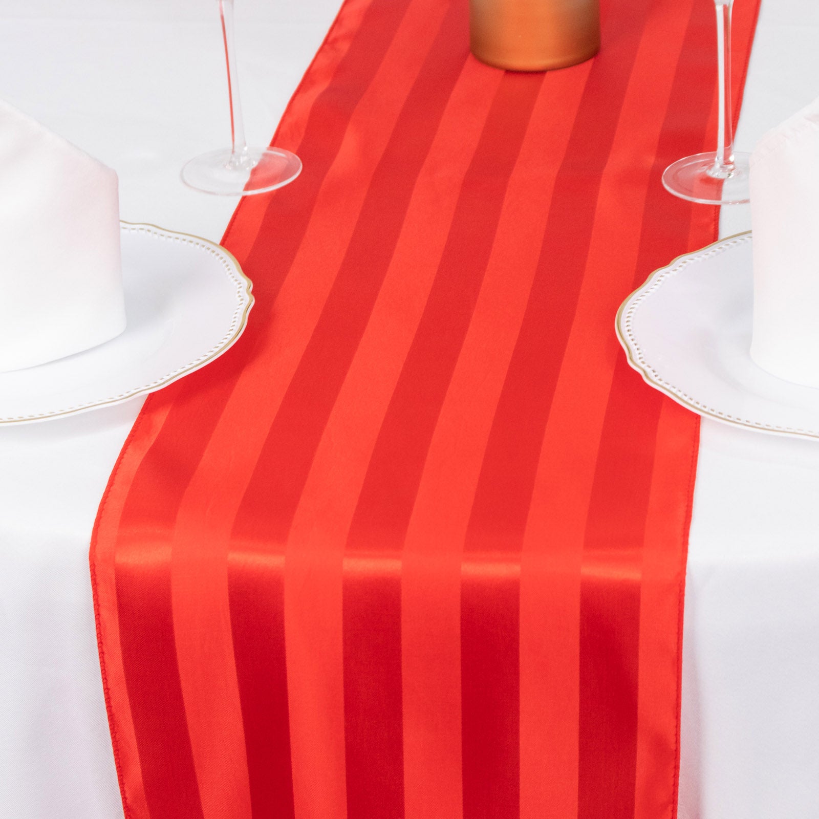 Red satin stripe table runner on a white table setting.