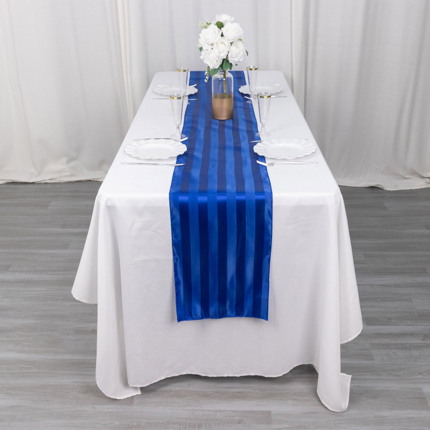 Royal blue satin stripe table runner on a white table setting.