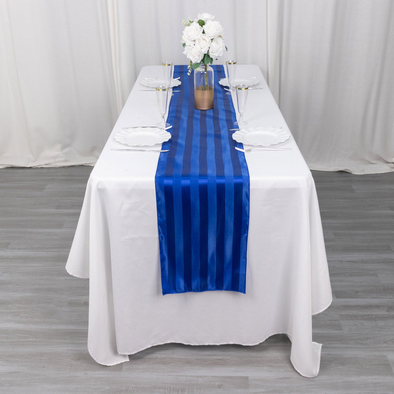 Royal blue satin stripe table runner on a white table setting.