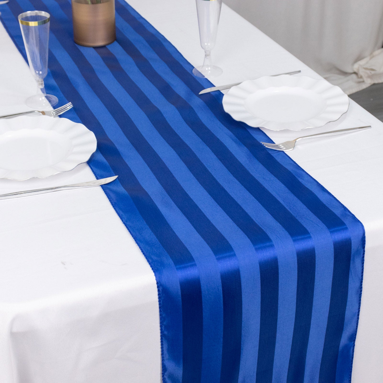 Royal blue satin stripe table runner on a white table setting.
