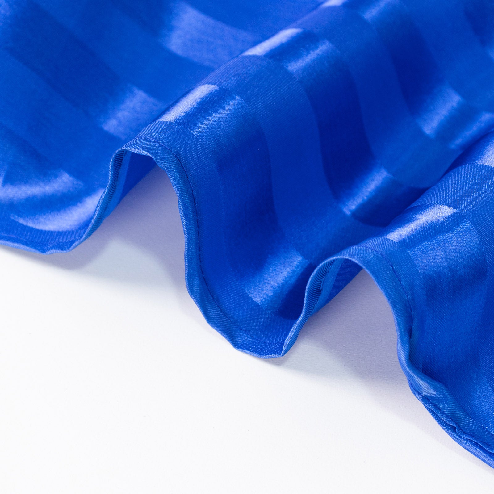 Royal blue satin stripe table runner on a white surface.