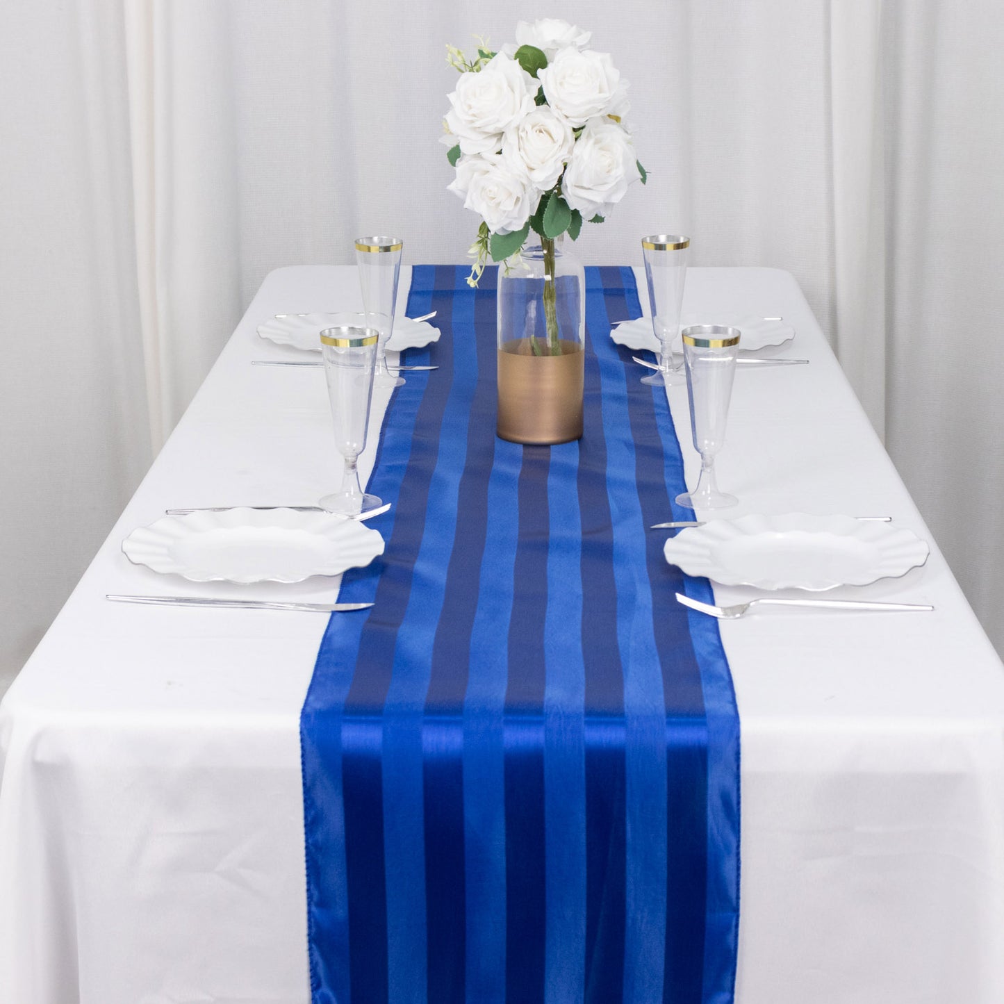 Royal blue satin stripe table runner on a white table setting.
