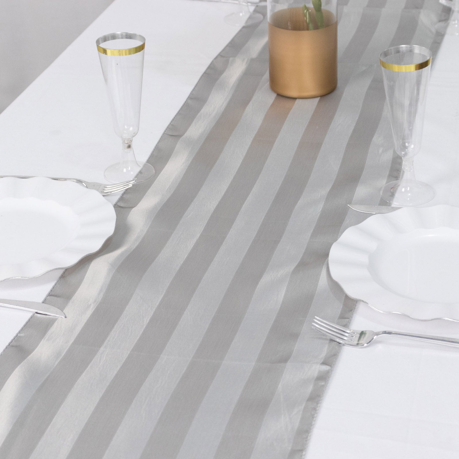 Silver satin stripe table runner on a dining table setting.
