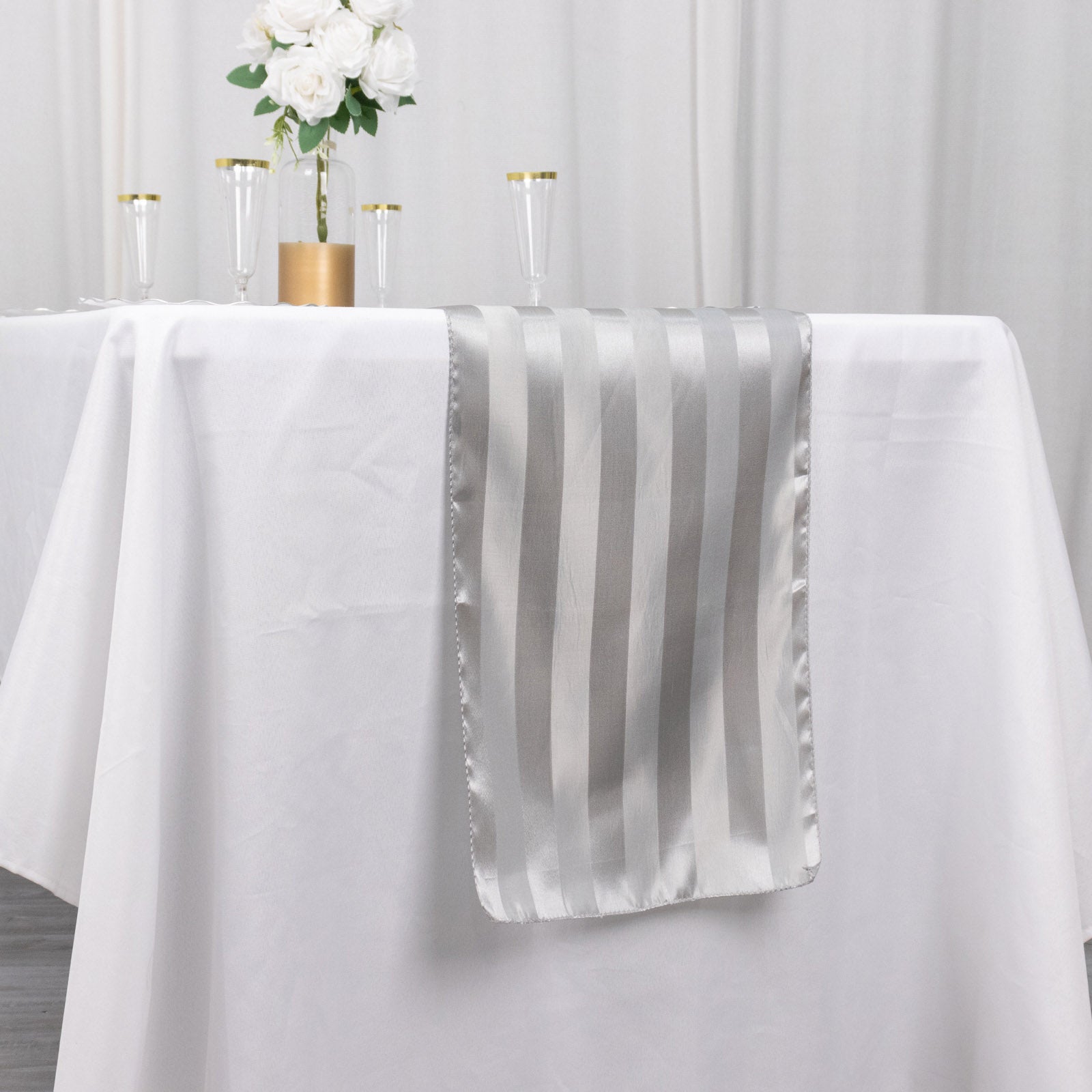 12"x108" silver satin stripe table runner on a white tablecloth.