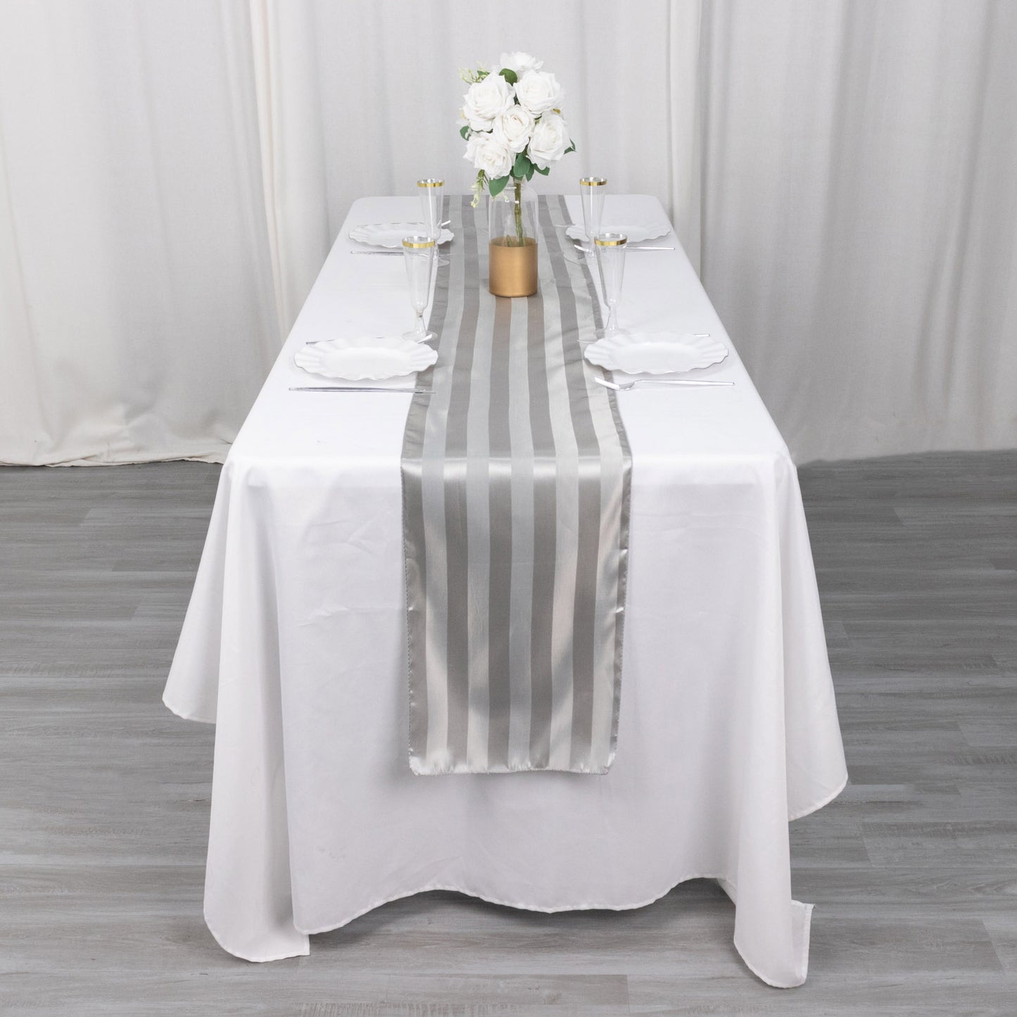 Silver satin stripe table runner on a white tablecloth.