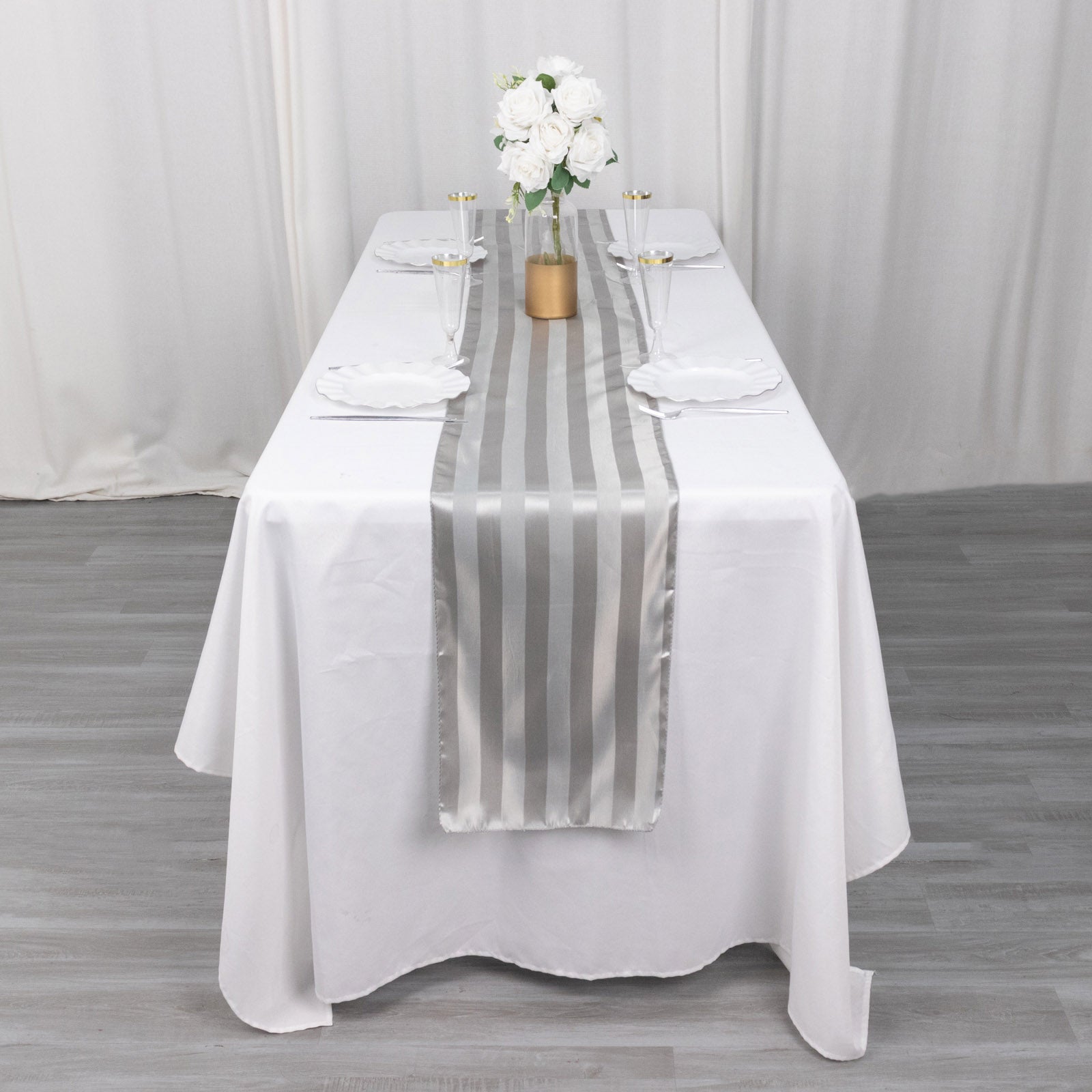 Silver satin stripe table runner on a white tablecloth.