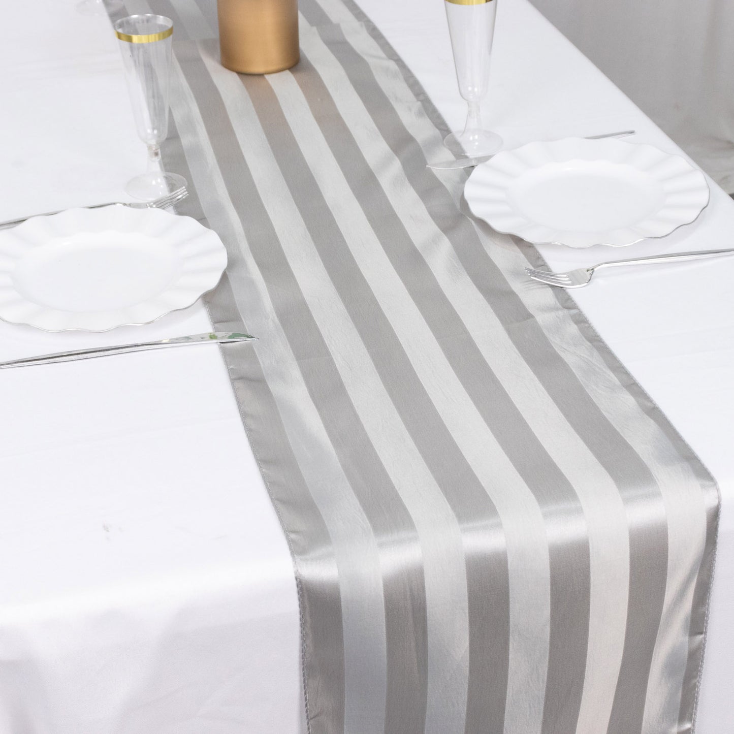 12"x108" silver satin stripe table runner on a white table.