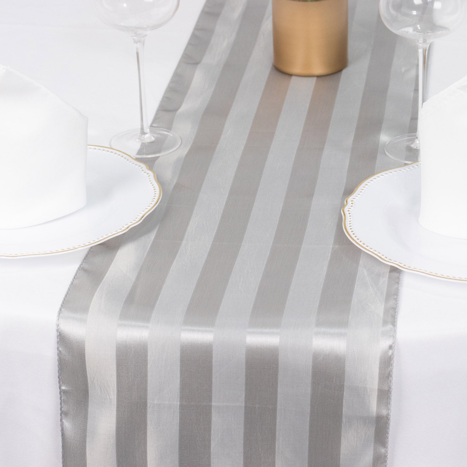 Silver satin stripe table runner on a dining table setting.