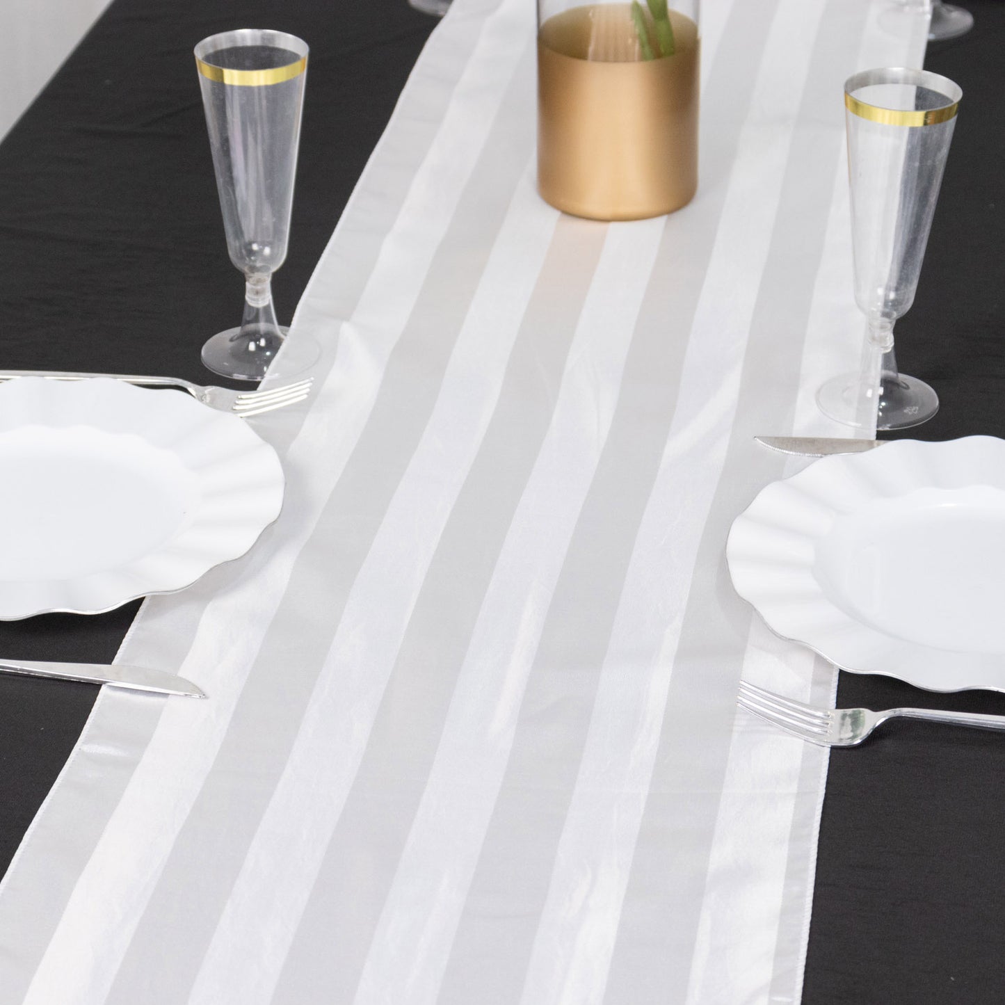 White satin stripe table runner on a black table setting.