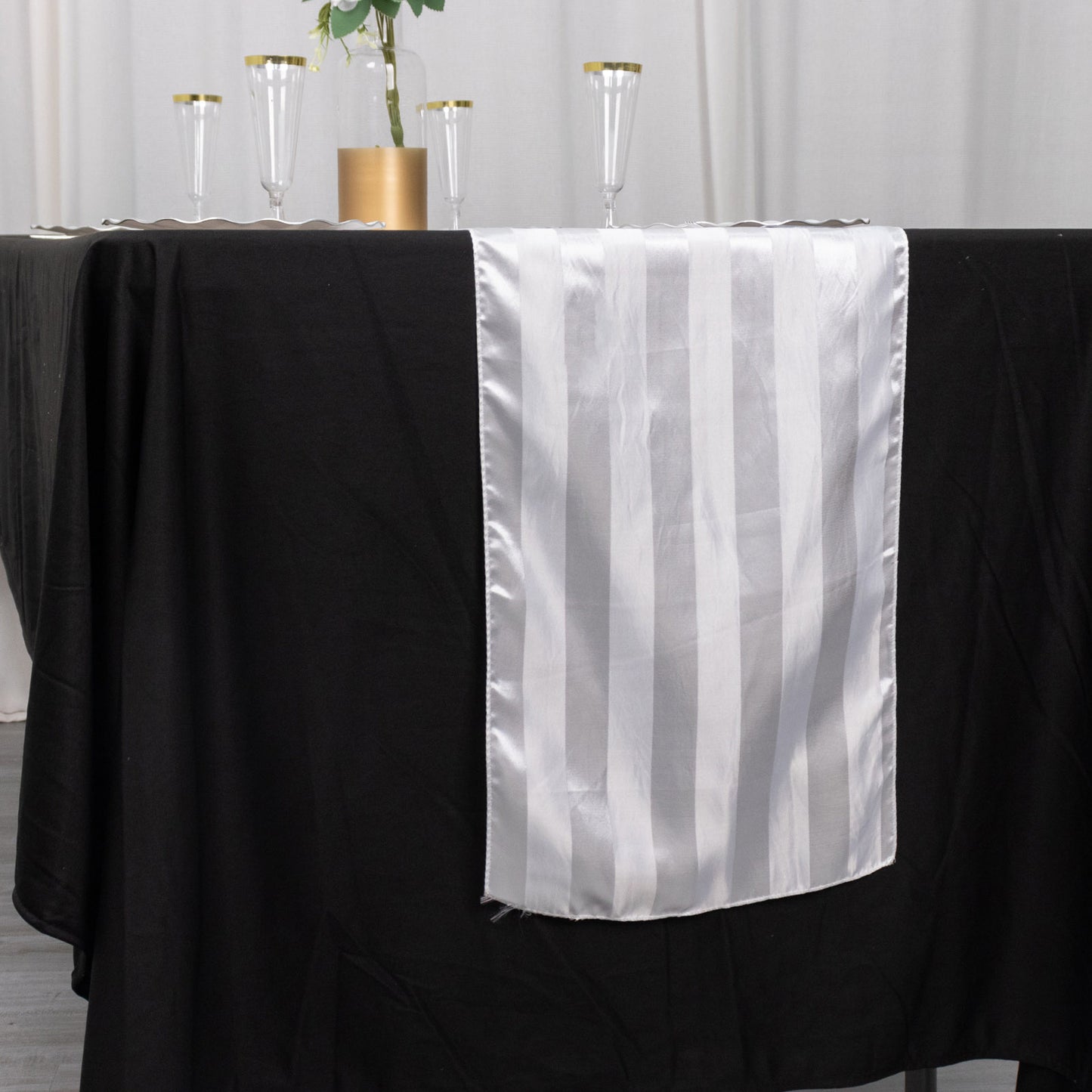 White satin stripe table runner on a black tablecloth.