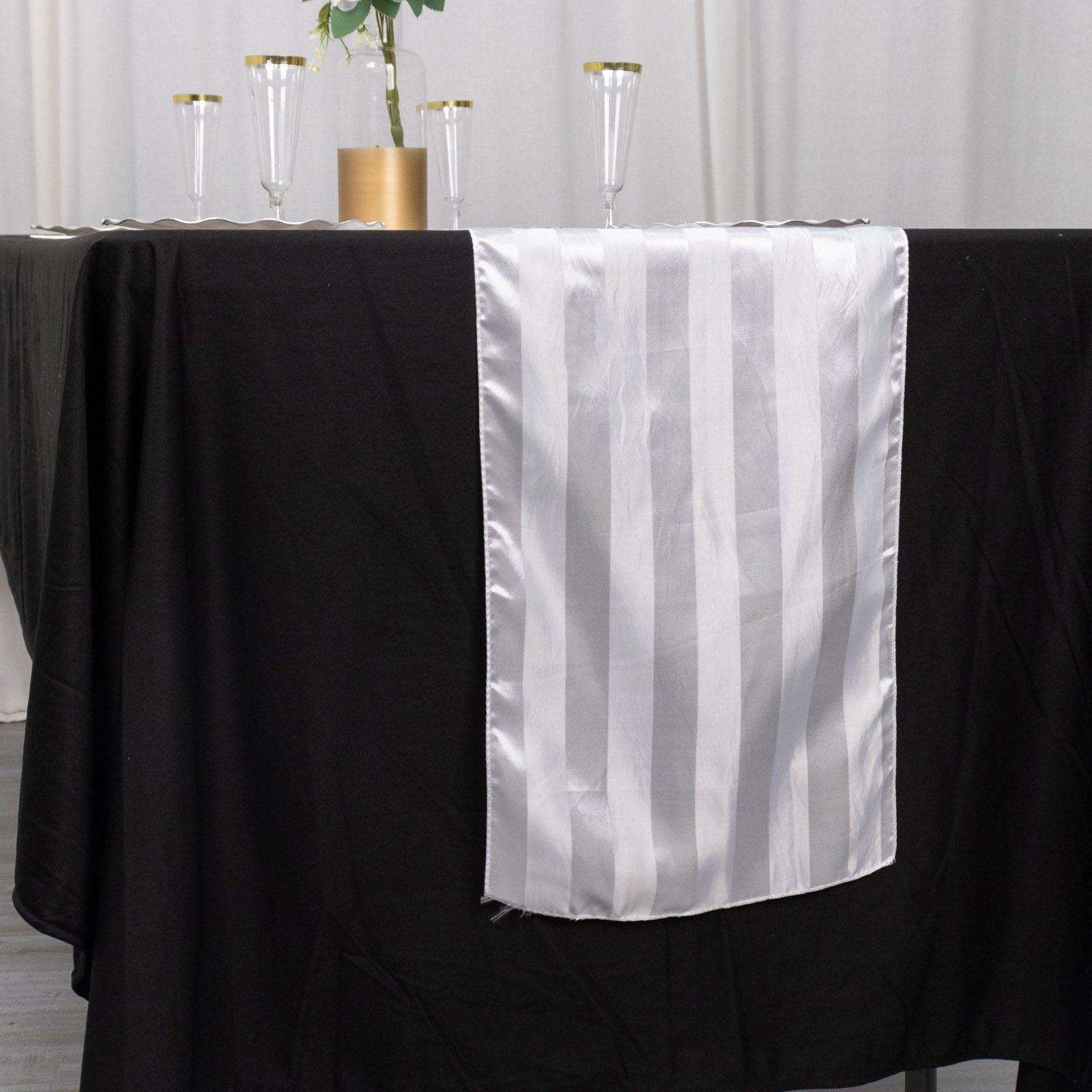 White satin stripe table runner on a black tablecloth.