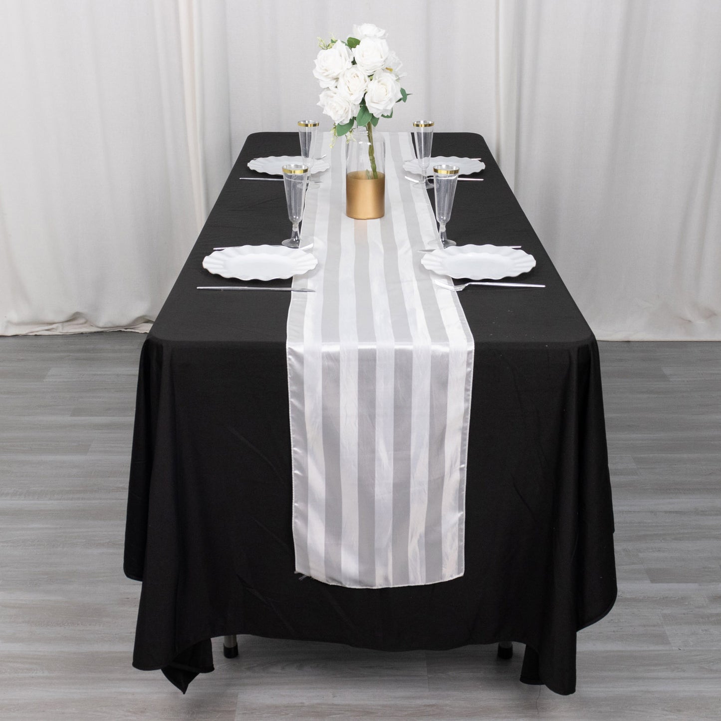White satin stripe table runner on a black tablecloth.
