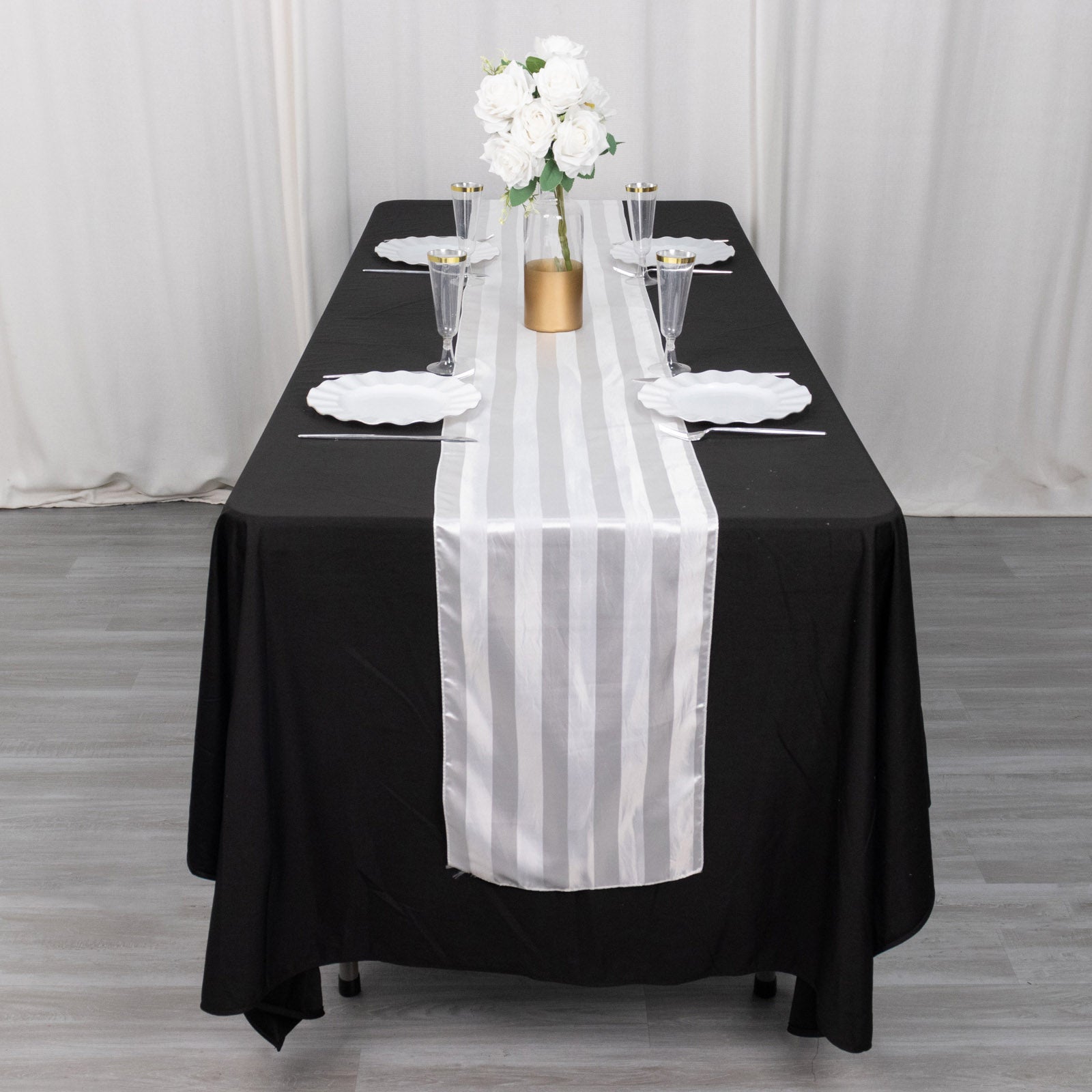 White satin stripe table runner on a black tablecloth.