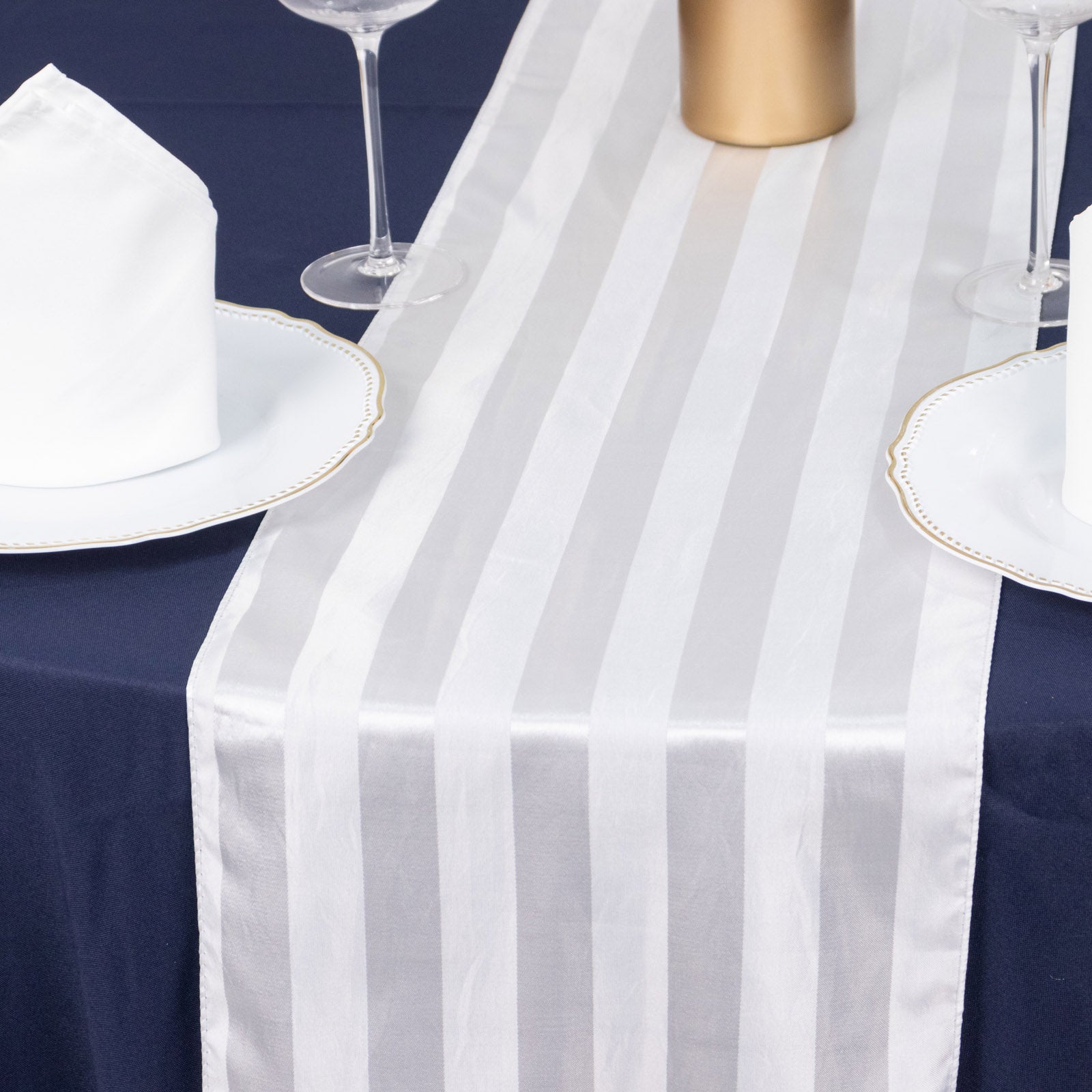 White satin stripe table runner on a dark blue tablecloth.