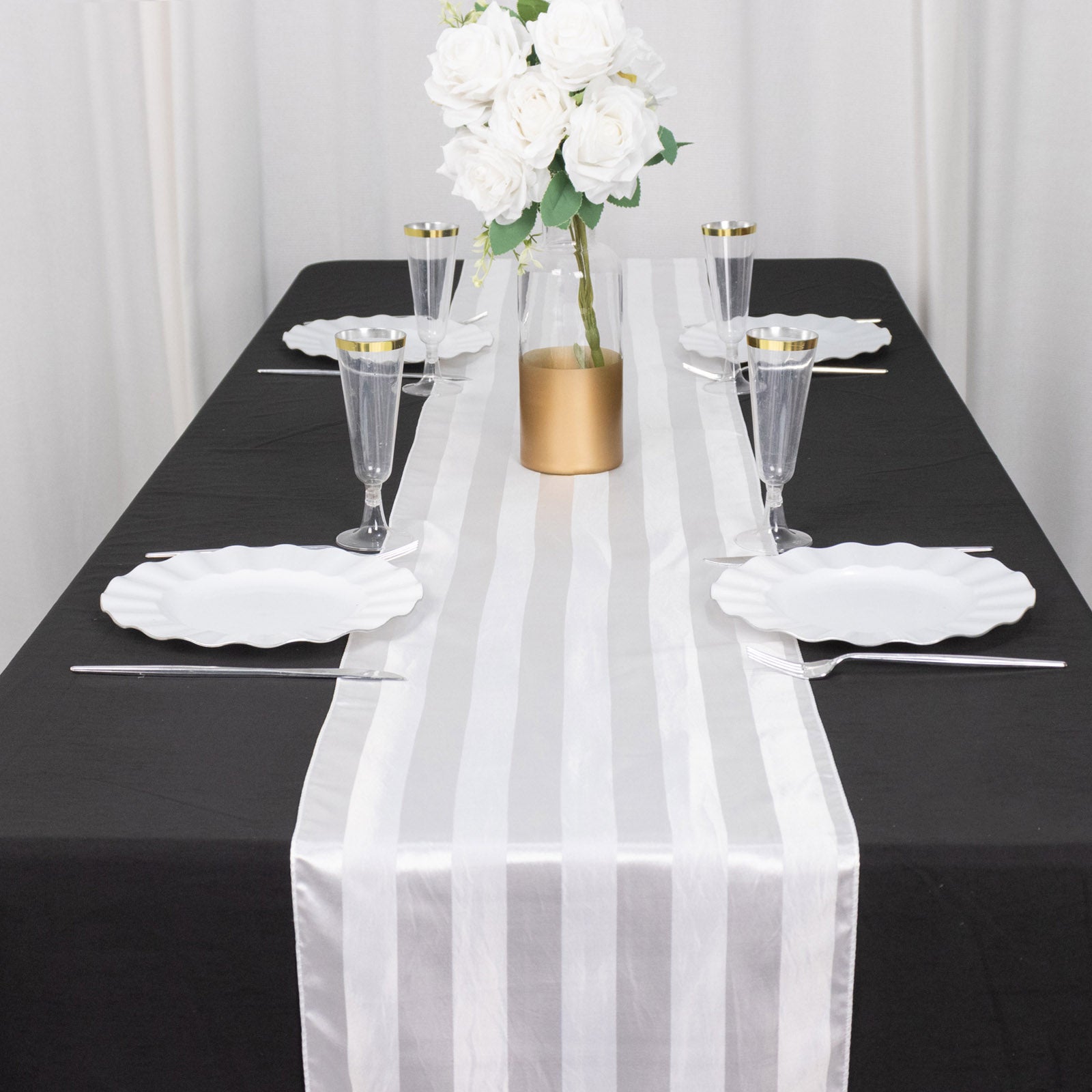 White satin stripe table runner on a black table with elegant decor.