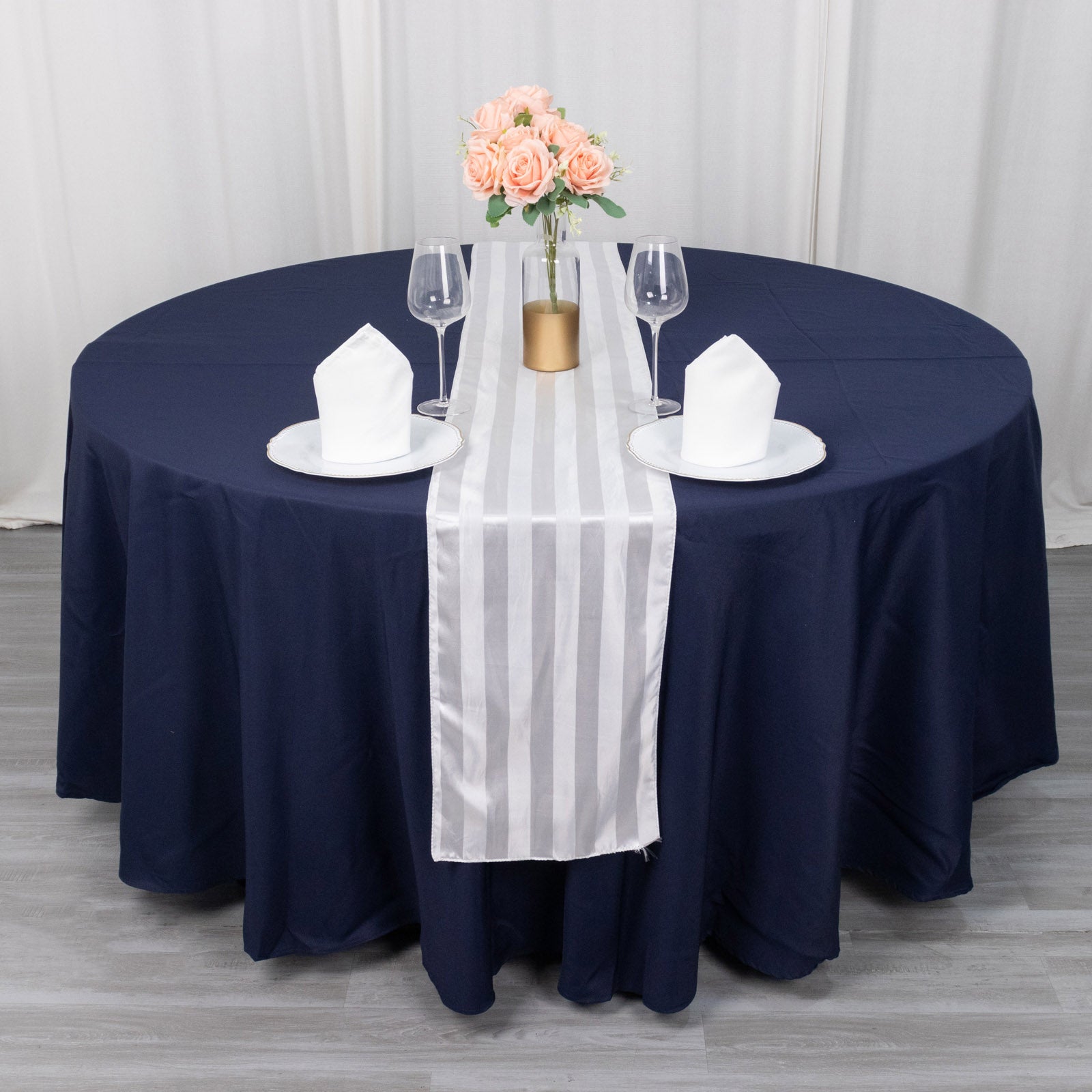 White satin stripe table runner on a dark blue tablecloth.