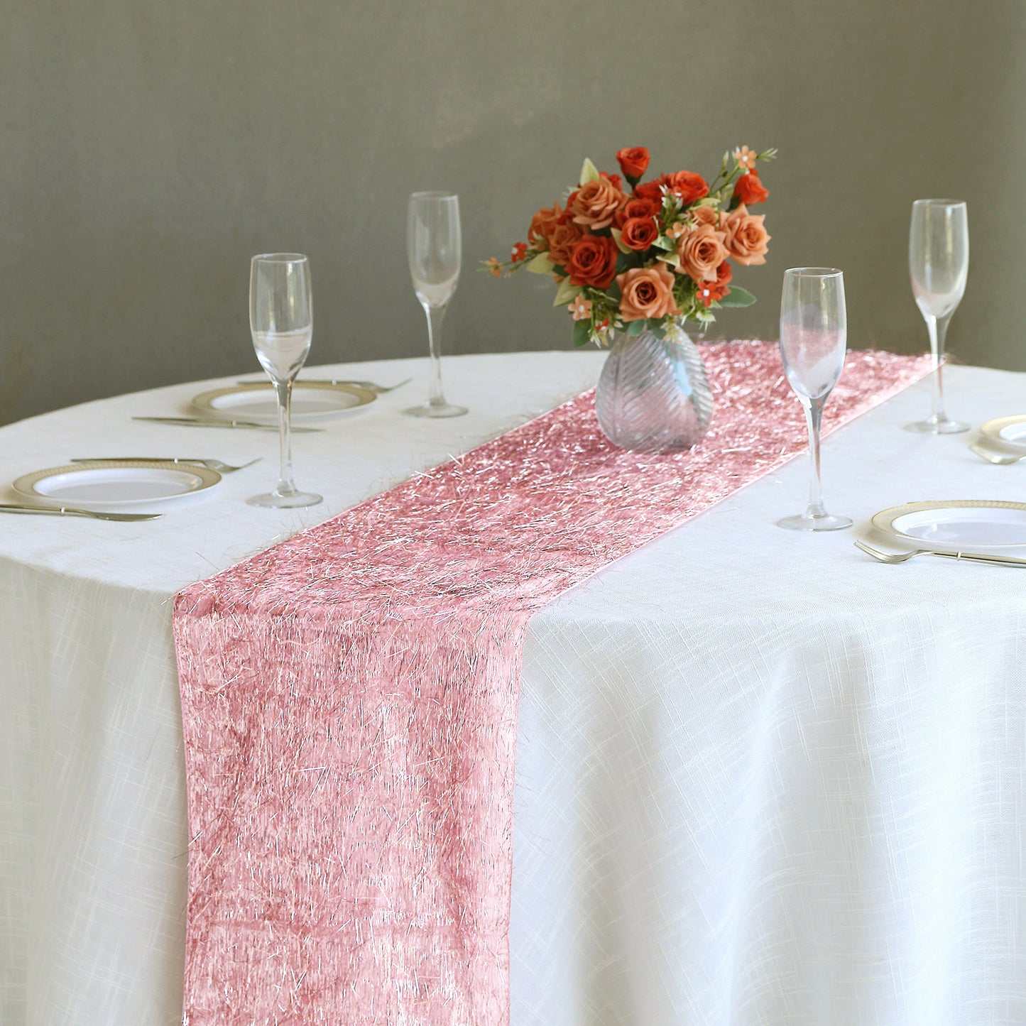 Rose gold metallic fringe tinsel table runner on a white table.