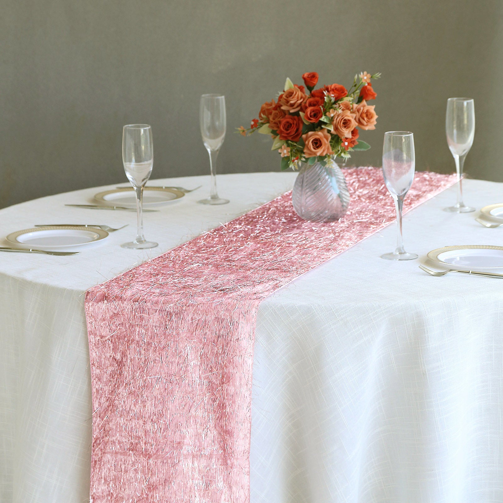 Rose gold metallic fringe tinsel table runner on a white table.