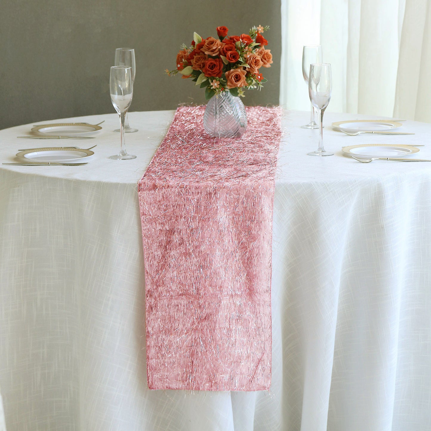 Rose gold metallic fringe shag tinsel table runner on a white table.