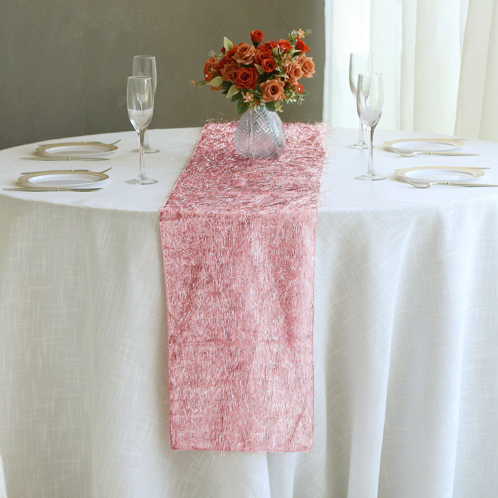 Rose gold metallic fringe shag tinsel table runner on a white table.