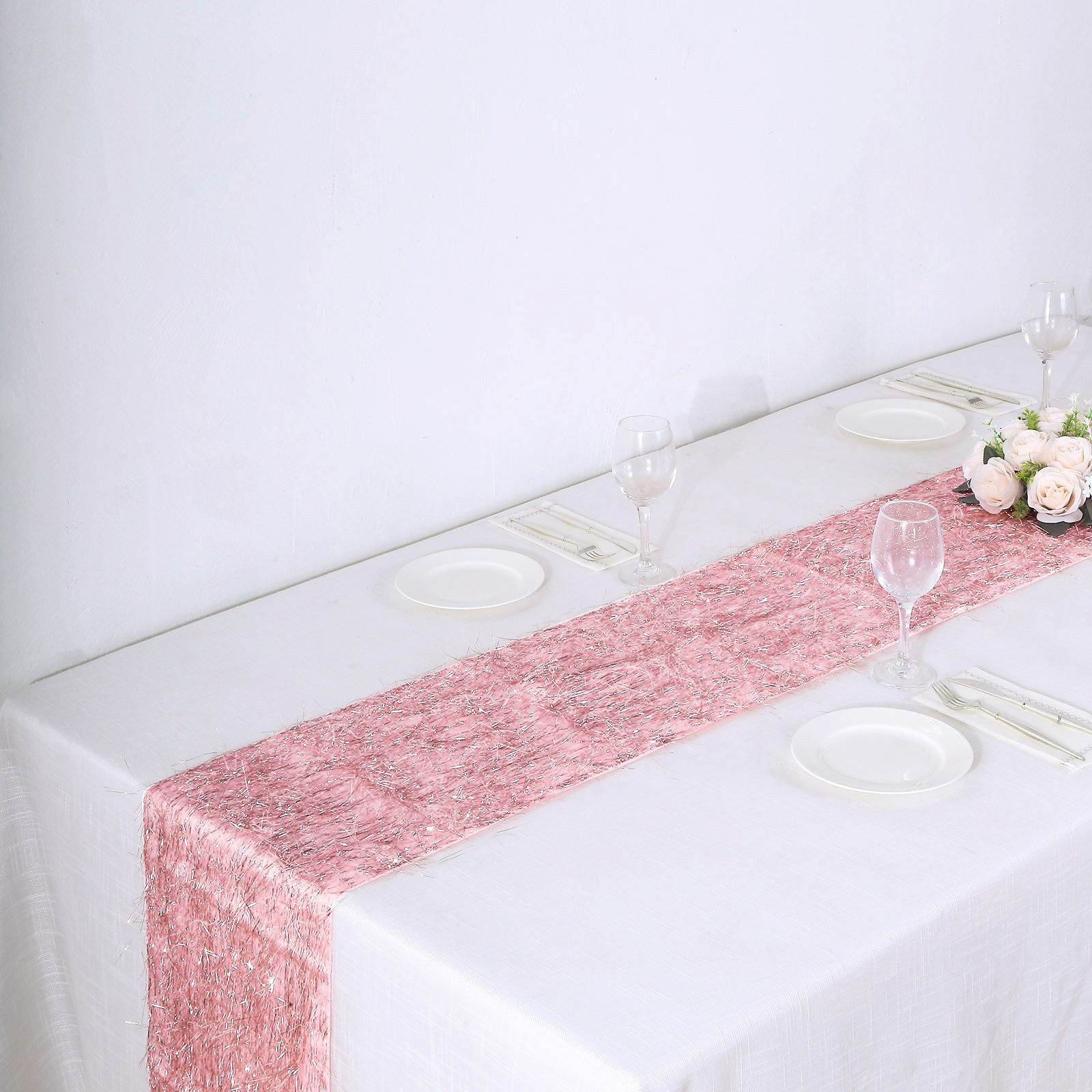 Rose gold metallic fringe tinsel table runner on a white table.