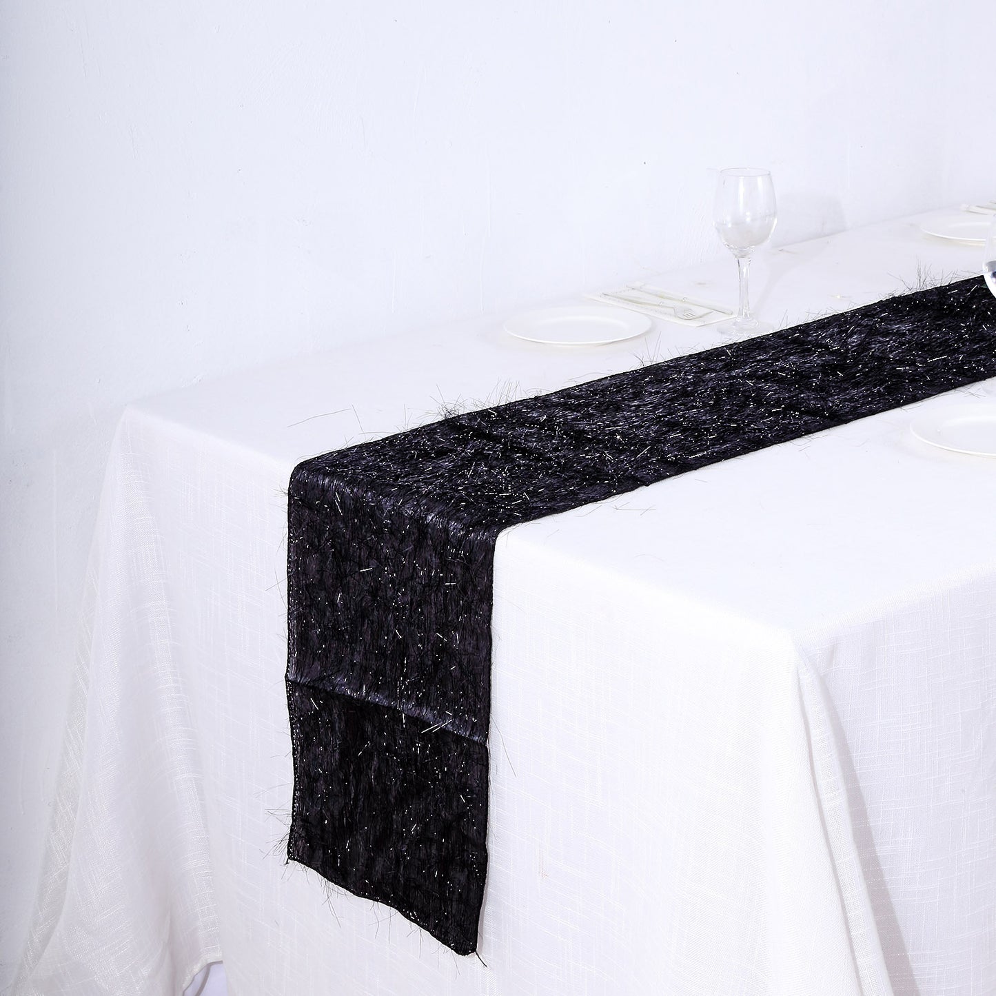 Black metallic fringe shag tinsel table runner on a white table.