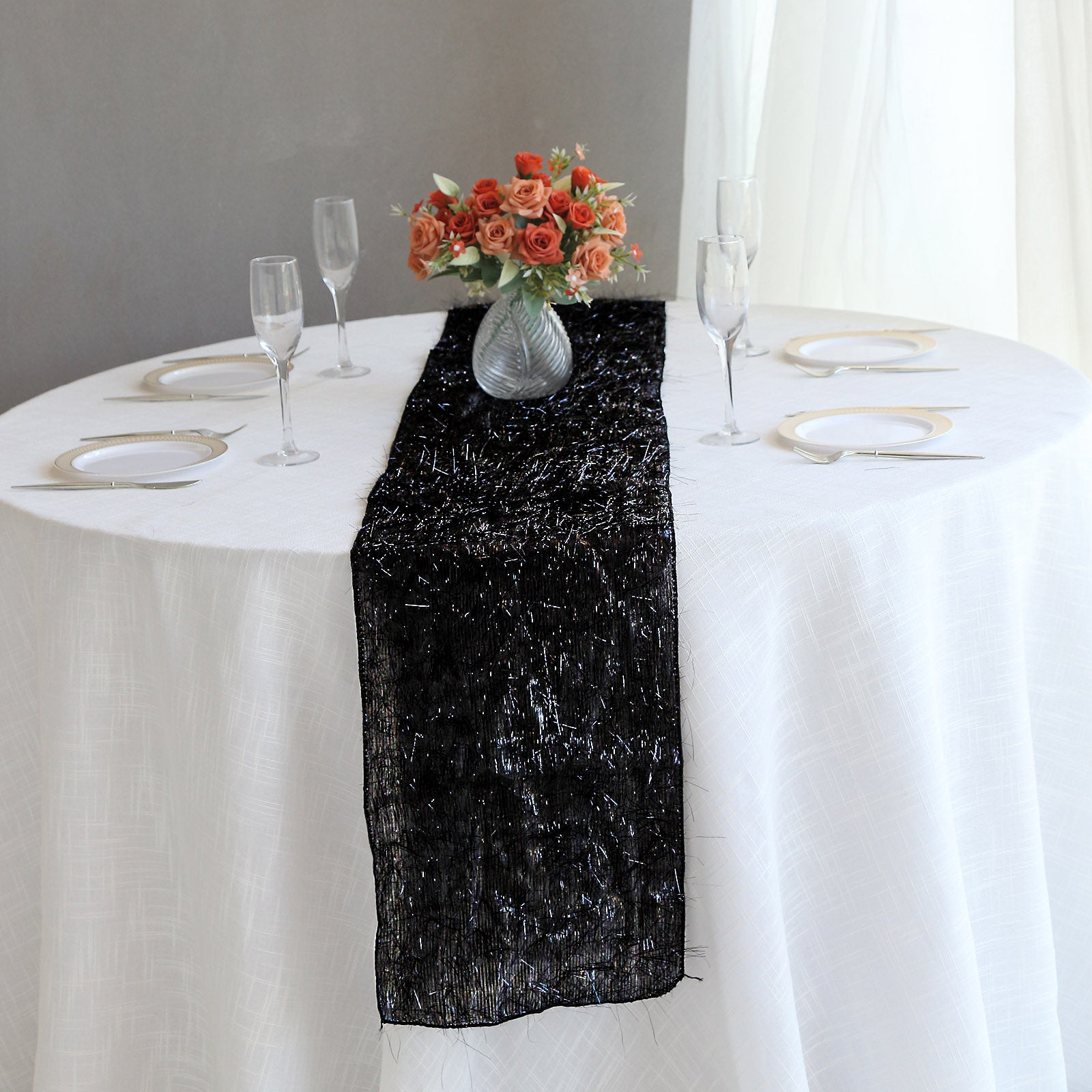 Black metallic fringe tinsel table runner on a white table.