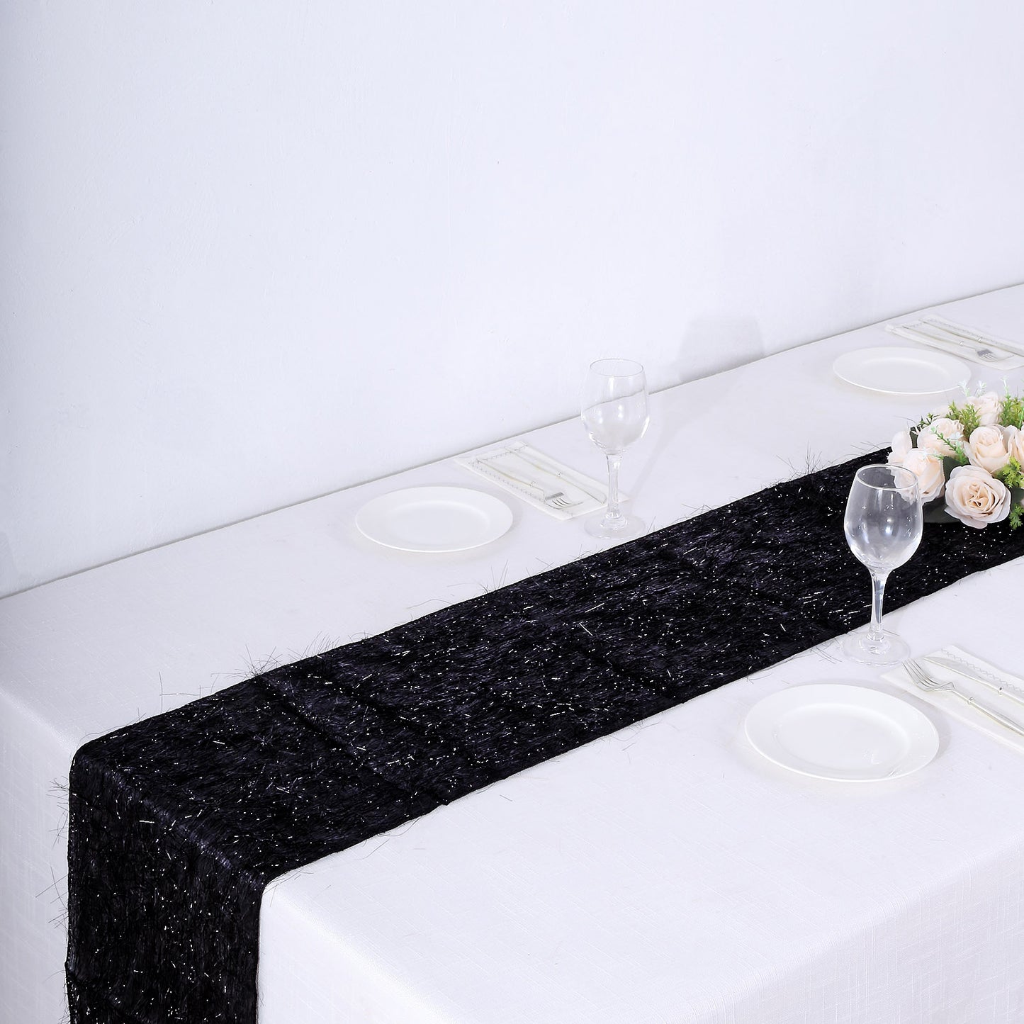 Black metallic fringe tinsel table runner on a white table setting.