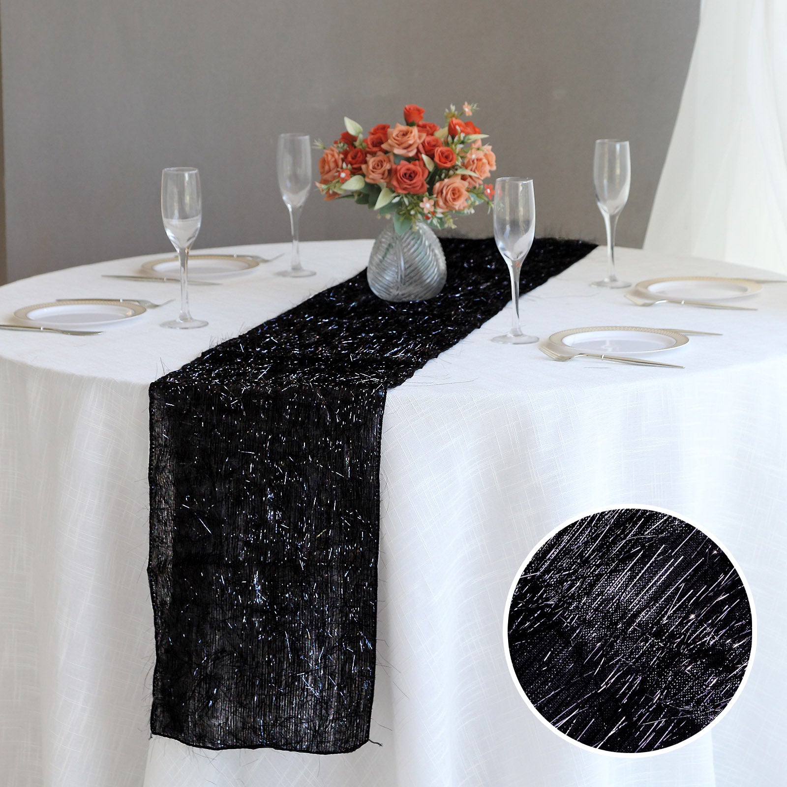 Black metallic fringe tinsel table runner on a white table setting.