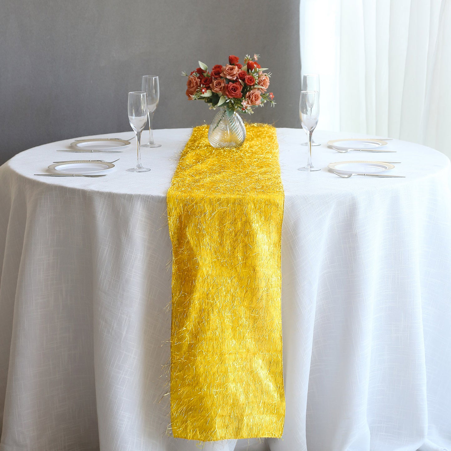 Gold metallic fringe table runner on a white tablecloth.