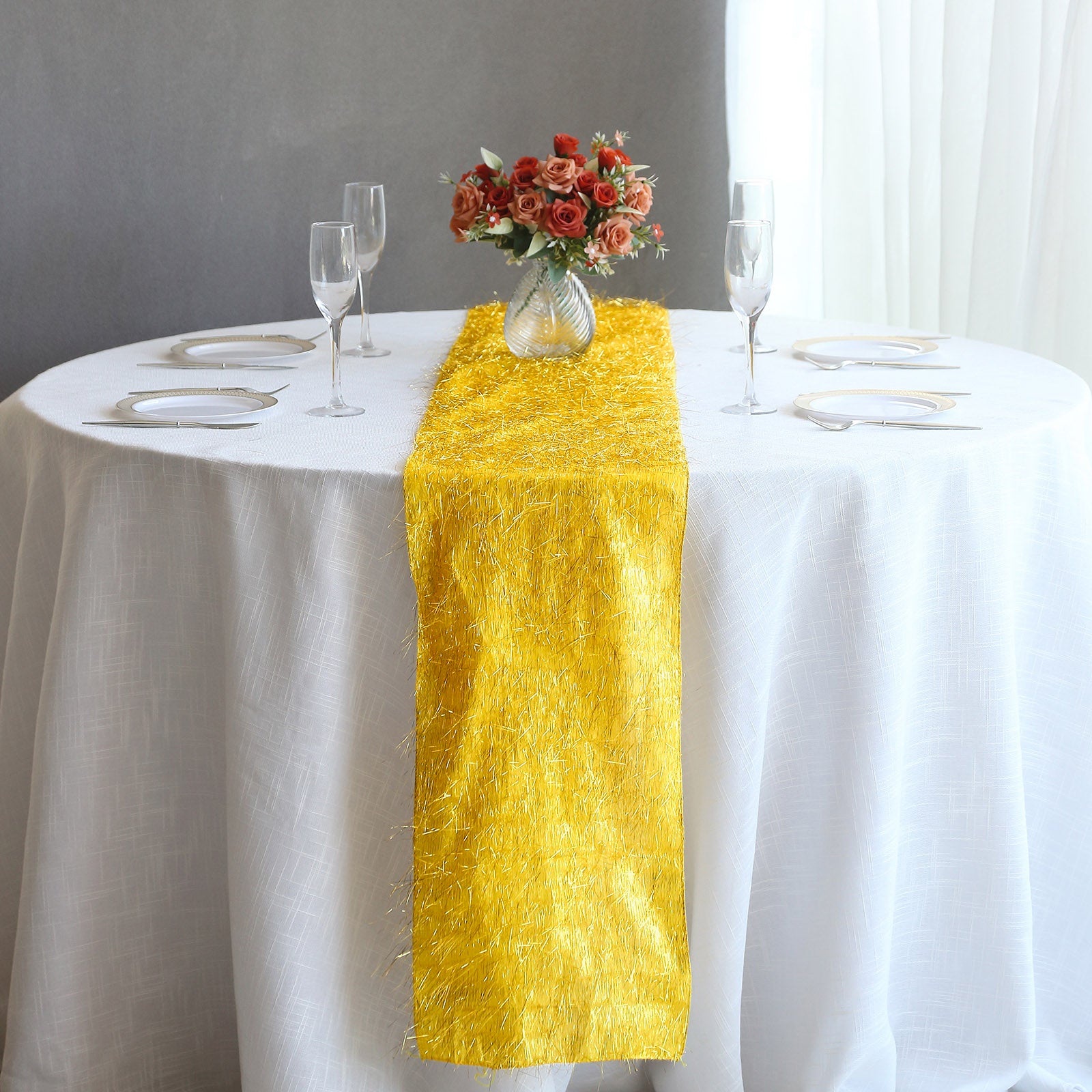 Gold metallic fringe table runner on a white tablecloth.