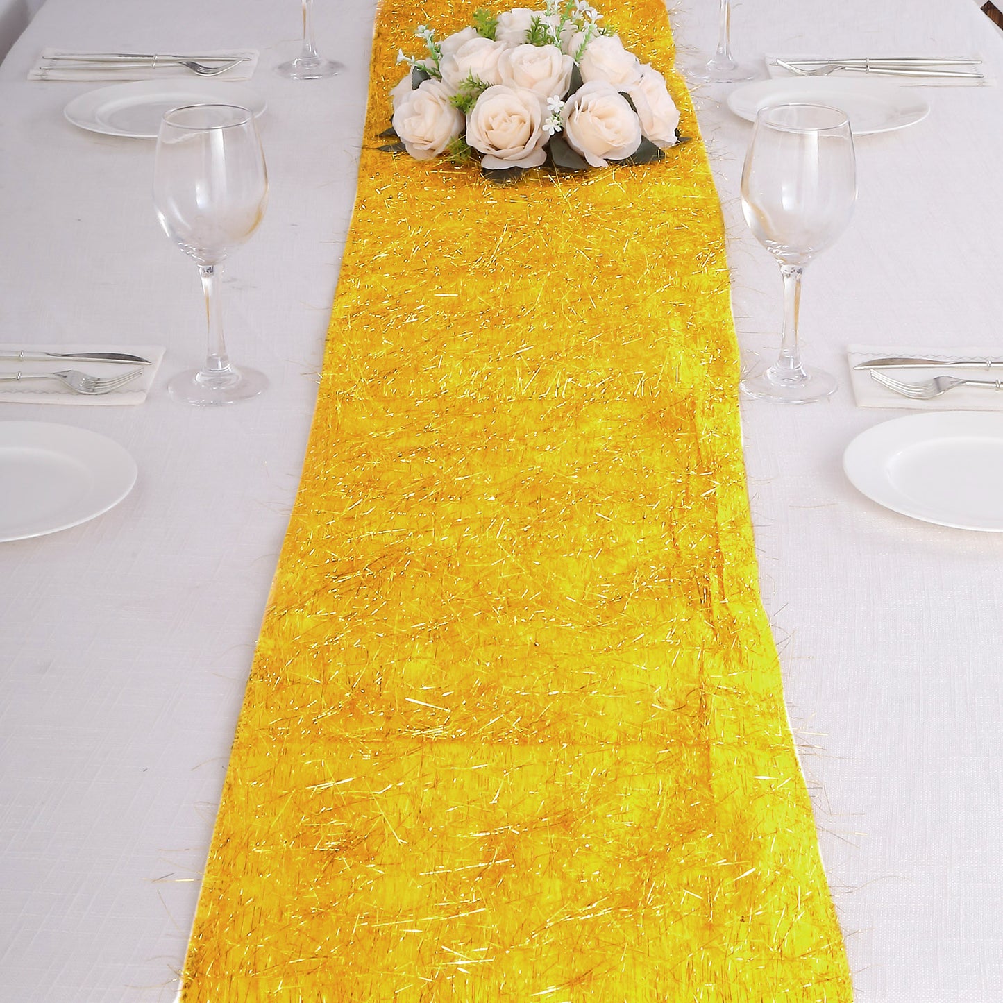 Gold metallic fringe table runner on a dining table with flowers.