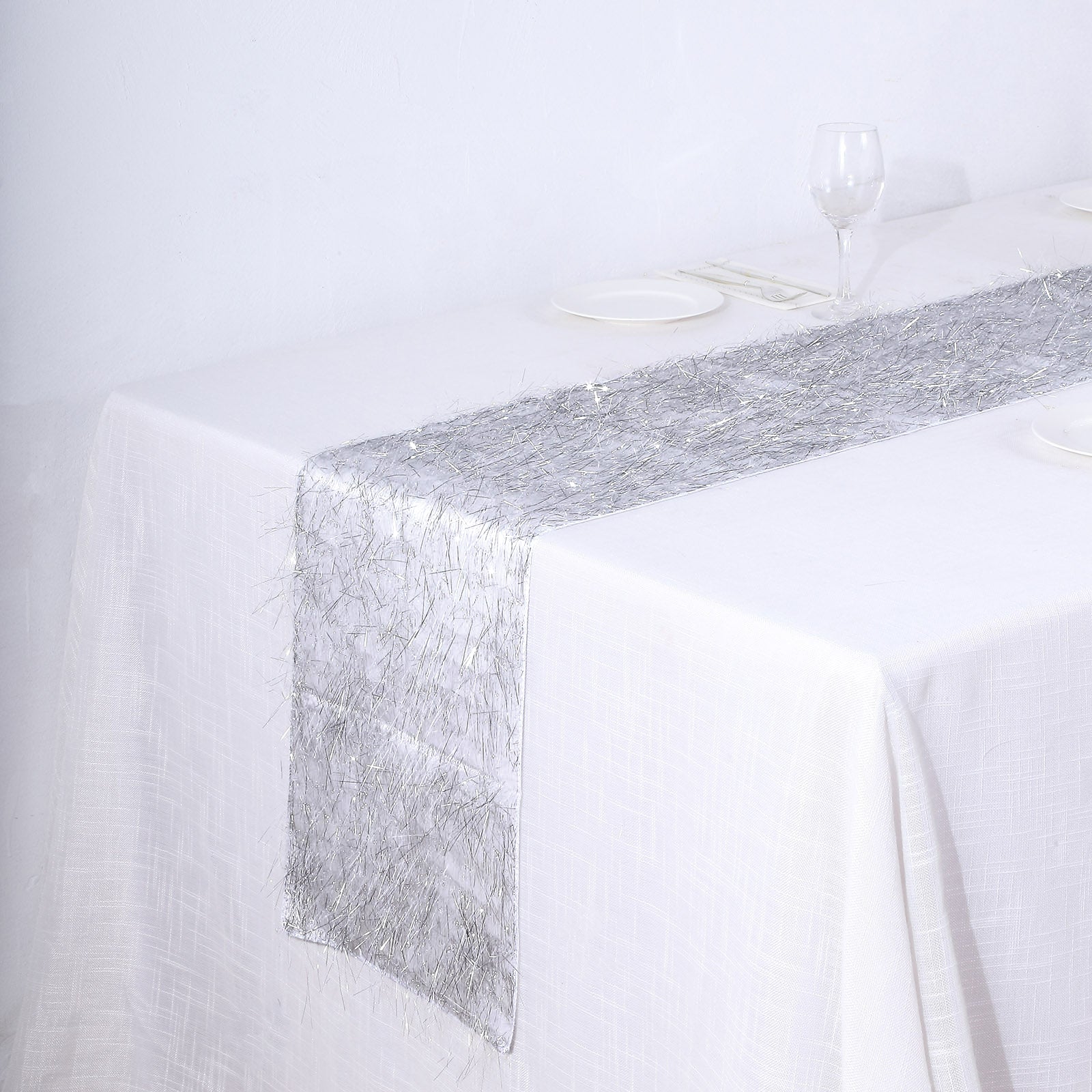Silver metallic fringe tinsel table runner on a white tablecloth.
