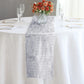 Silver metallic fringe tinsel table runner on a white tablecloth.