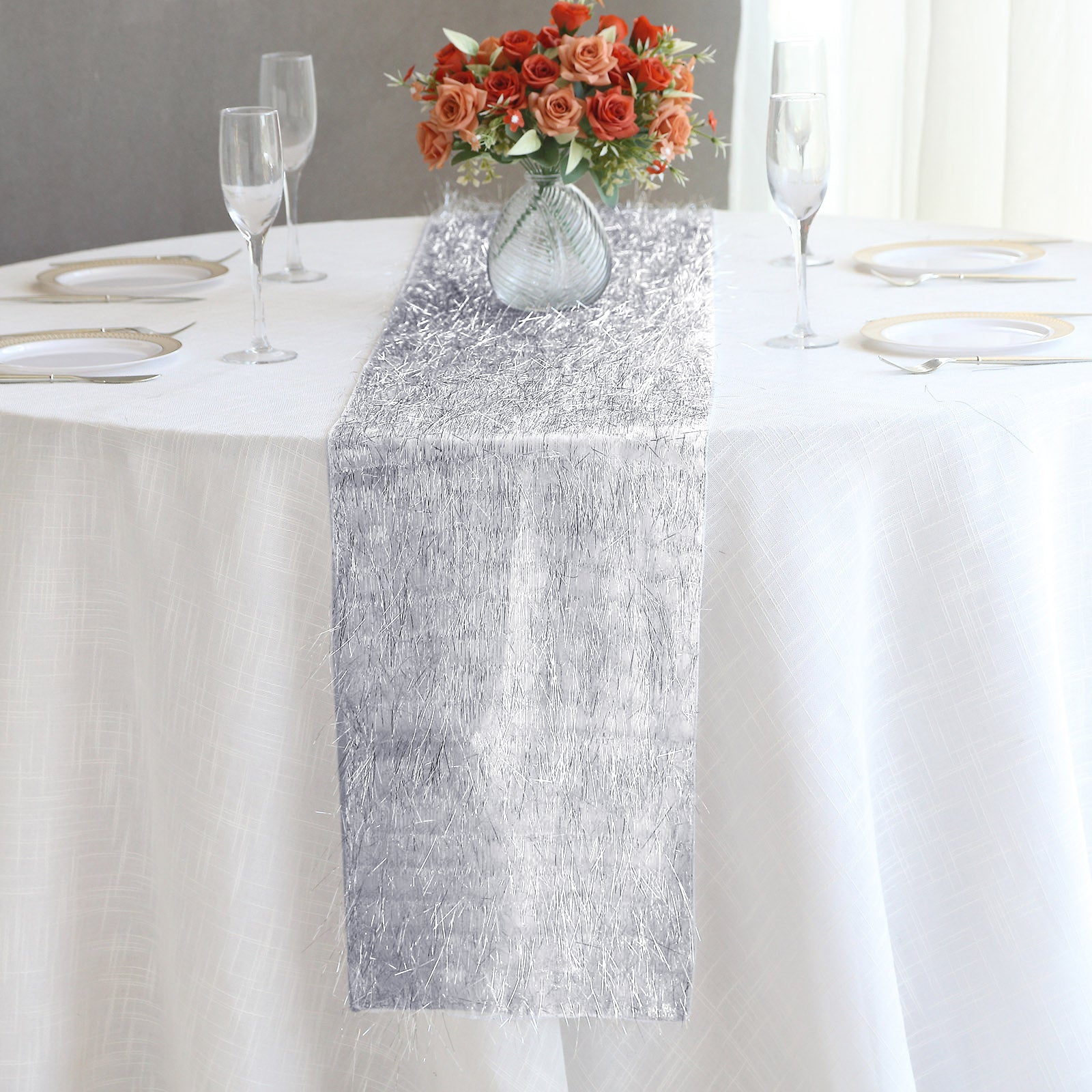 Silver metallic fringe tinsel table runner on a white tablecloth.