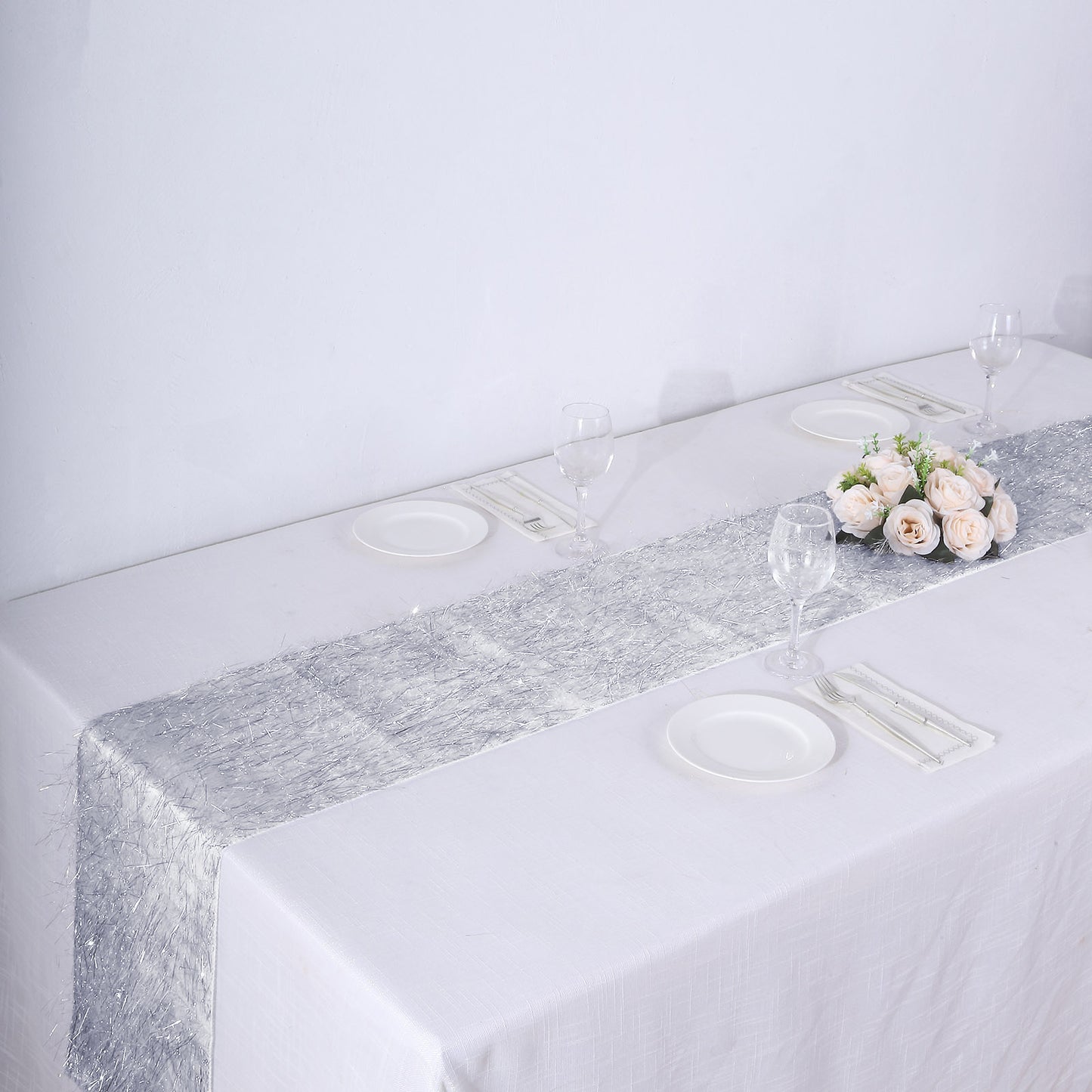 Silver metallic fringe shag tinsel table runner on a white table.