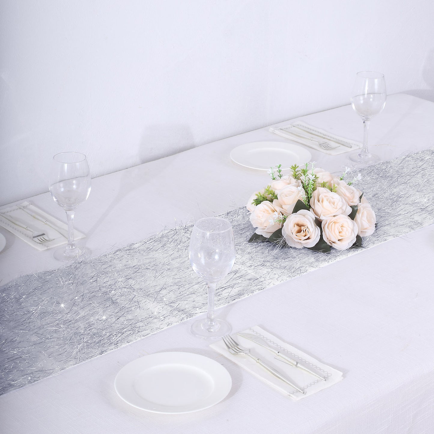 Silver metallic fringed table runner on a white table setting.