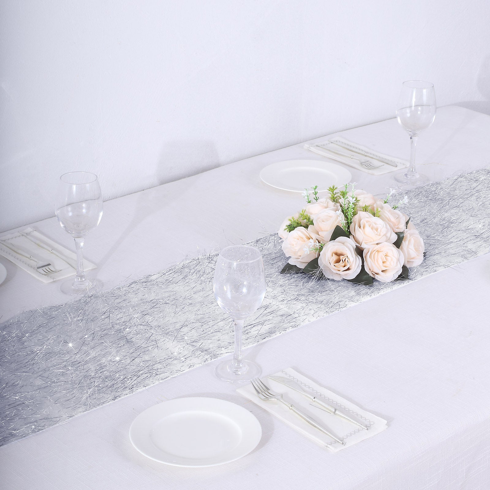 Silver metallic fringed table runner on a white table setting.