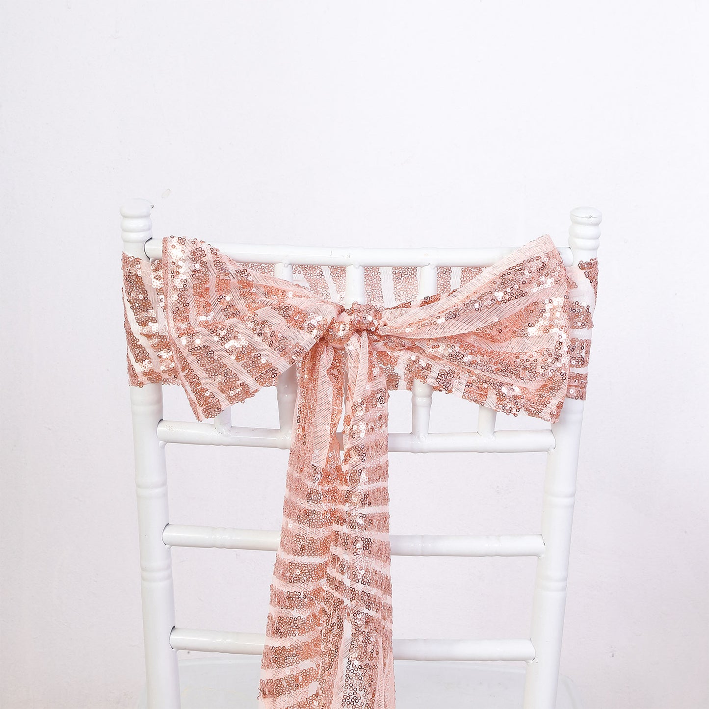 Rose gold geometric diamond sequin chair sash on a white chair.