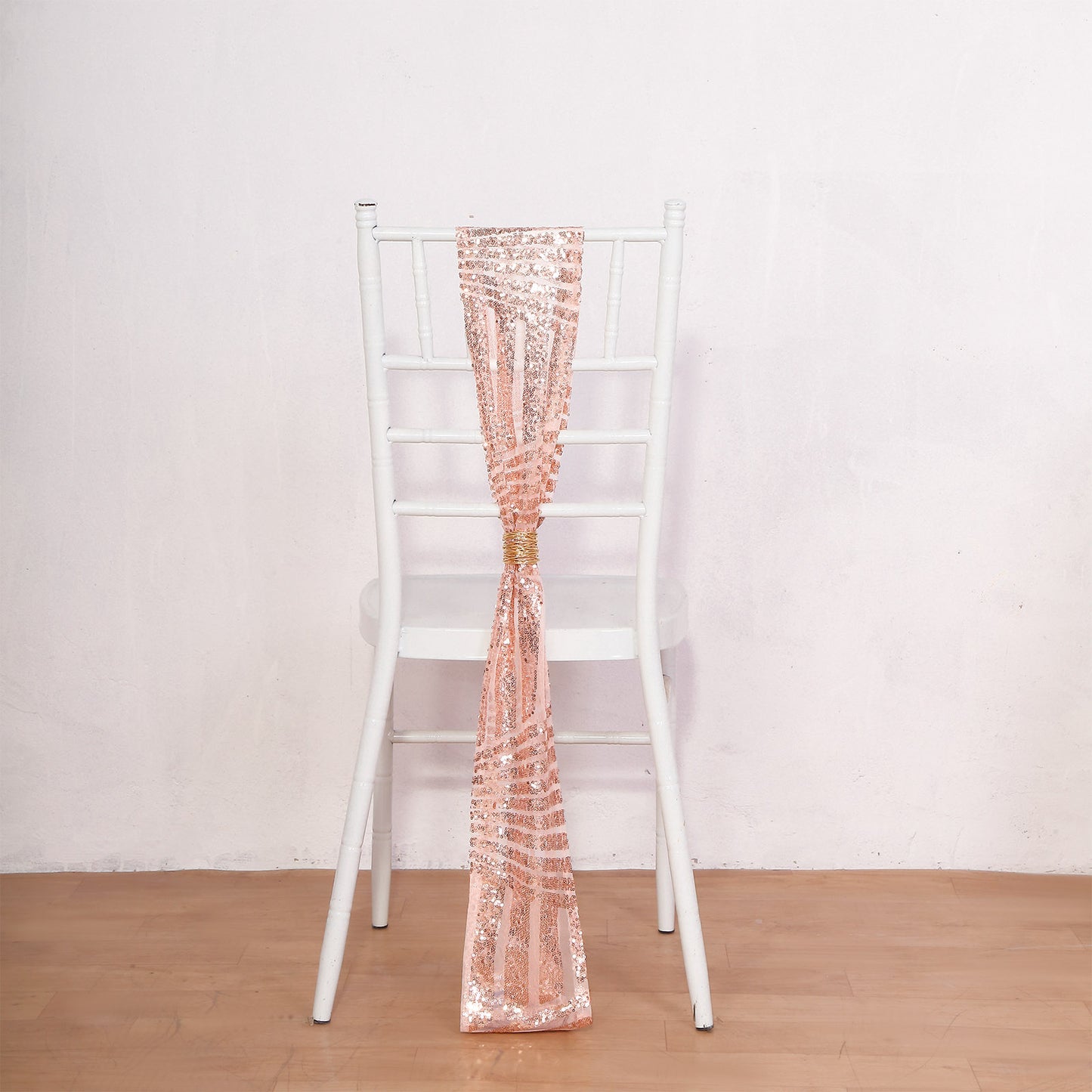 Rose gold geometric sequin chair sash draped on a white chair.