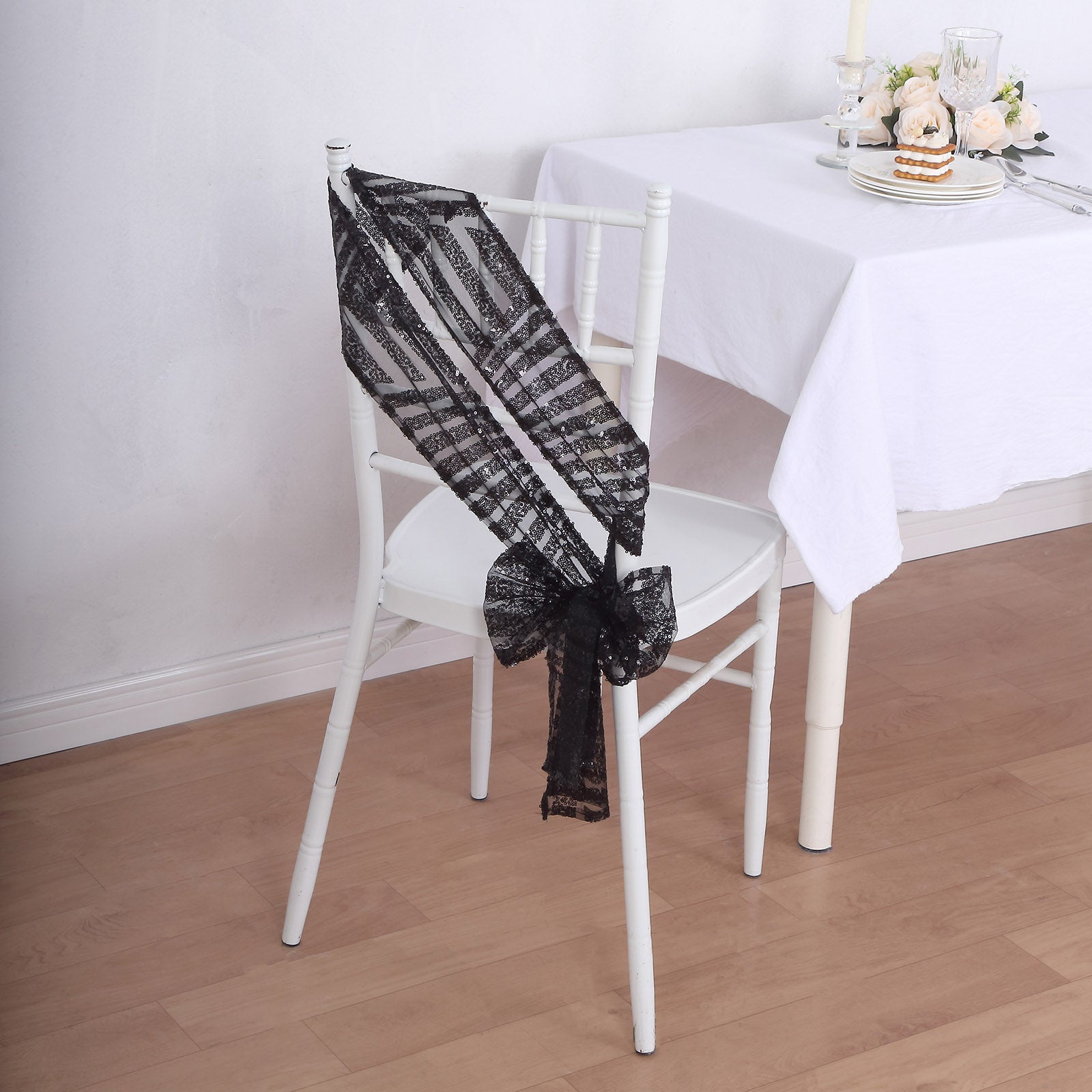 Black geometric diamond glitz sequin chair sash on a white chair.