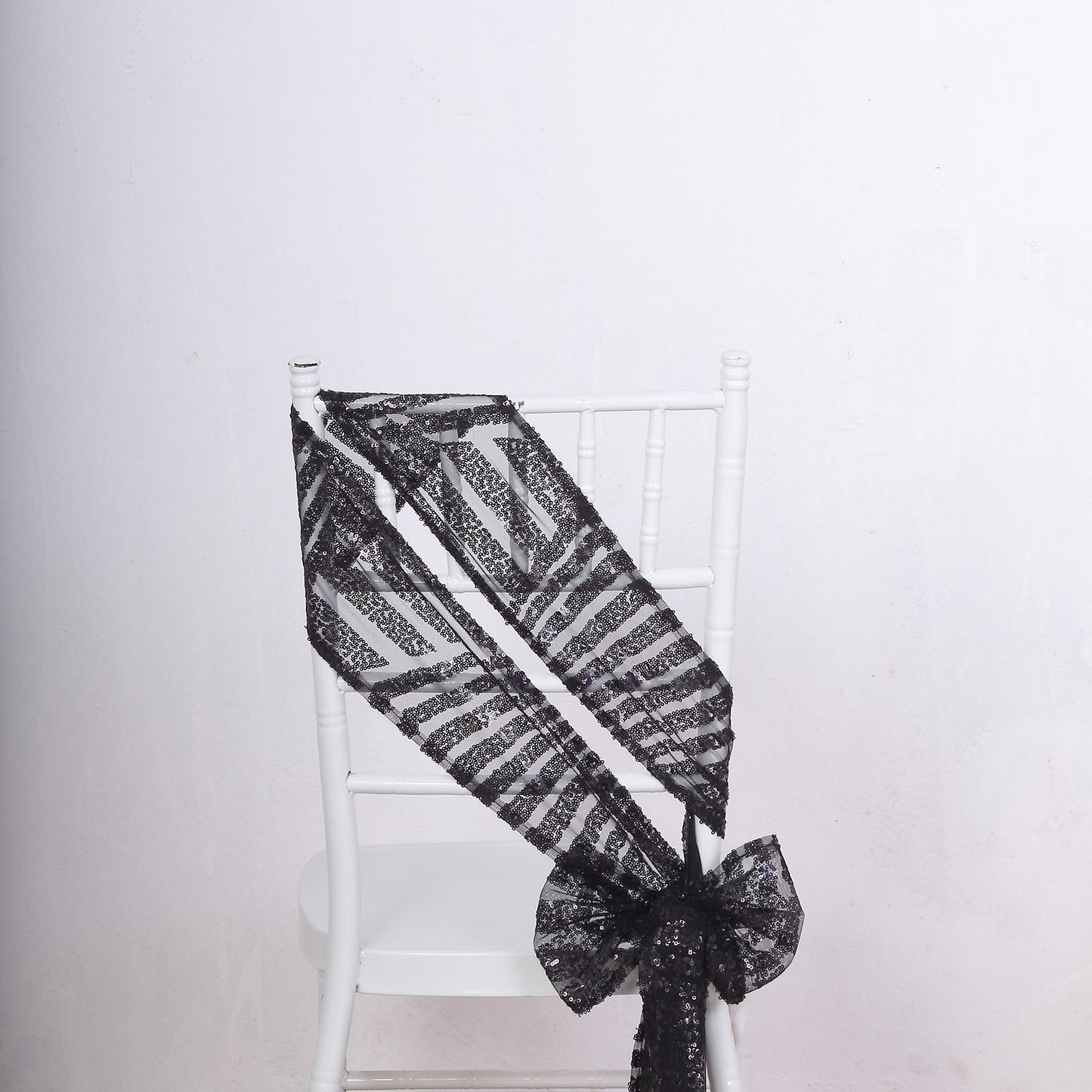 Black geometric diamond glitz sequin chair sash on a white chair.