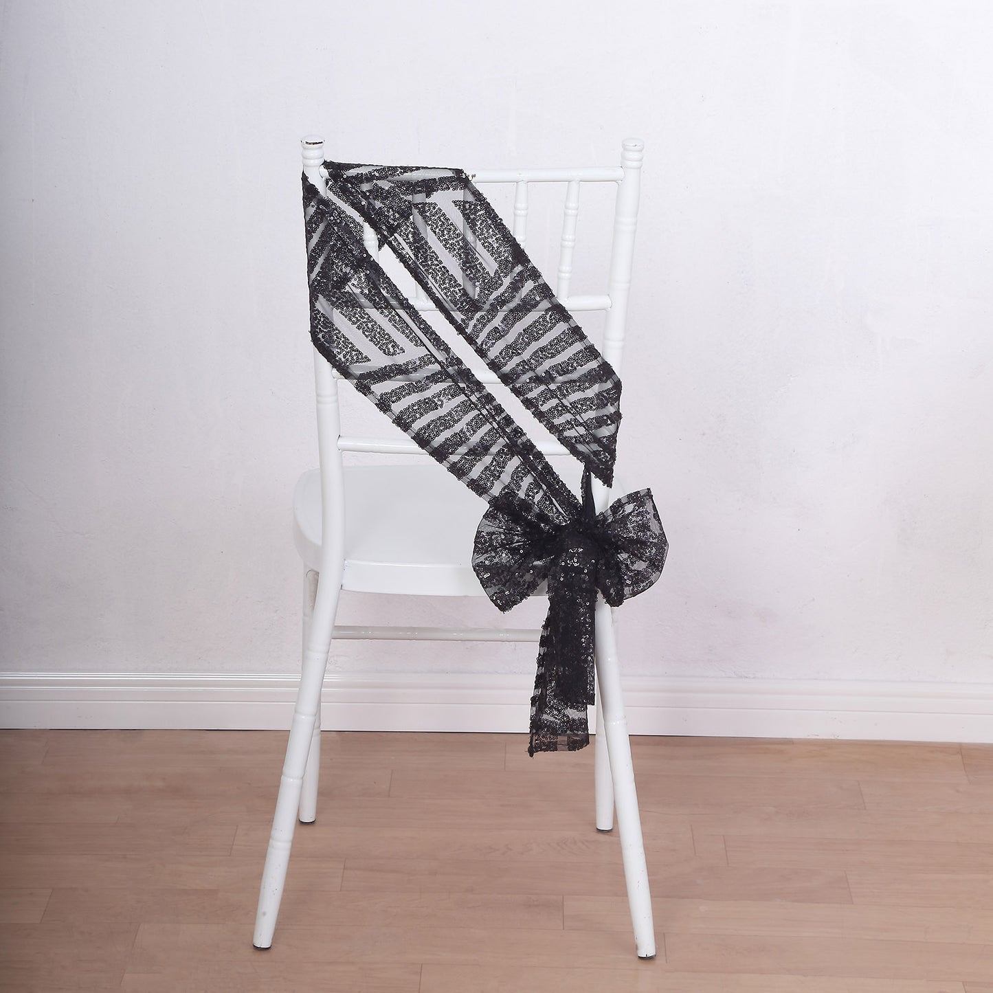 Black geometric diamond glitz sequin chair sash on a white chair.