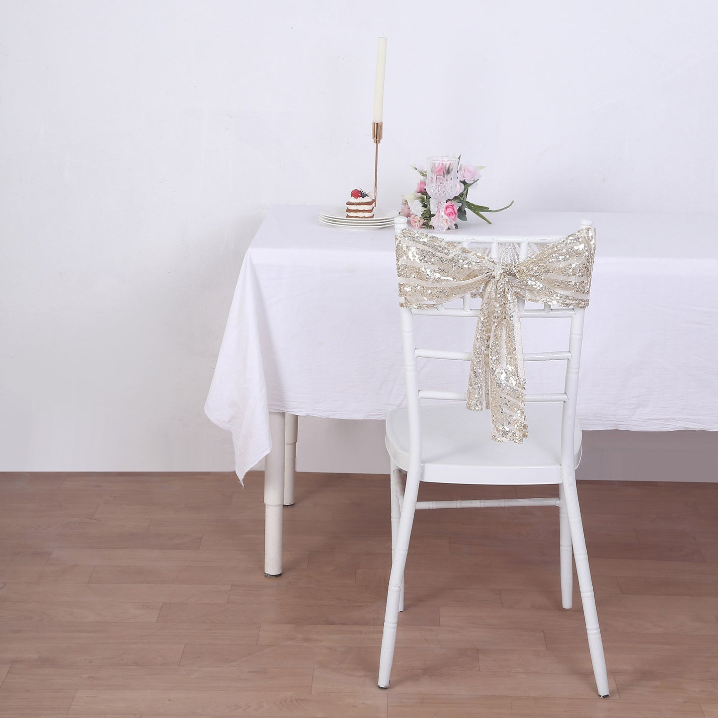 Champagne sequin chair sash on a white chair at a decorated table.